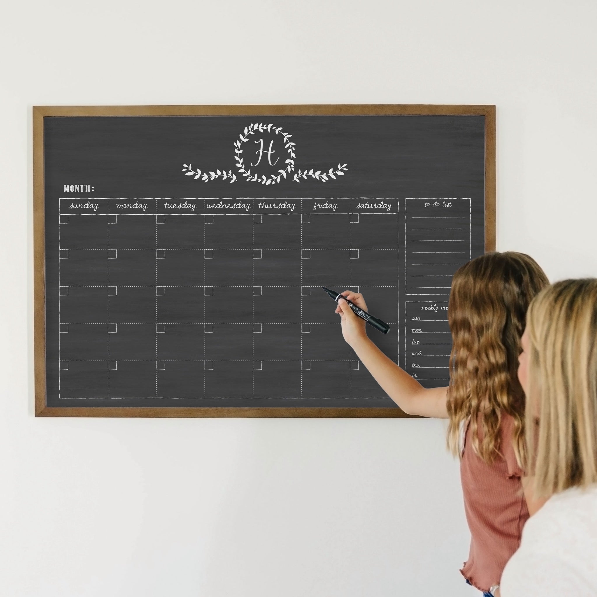 A framed whiteboard monthly calender hanging on the wall