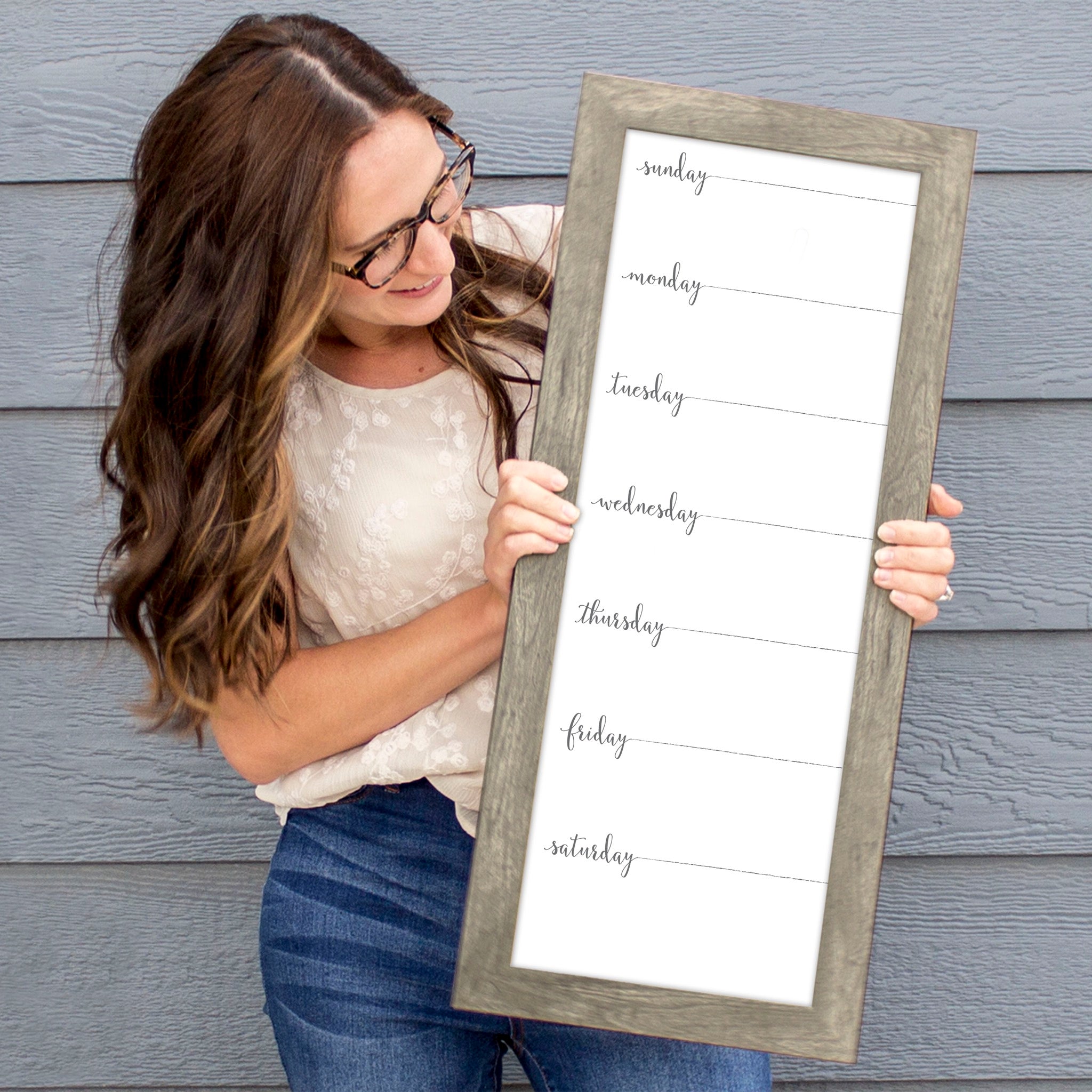 A framed slim whiteboard weekly calender hanging on the wall