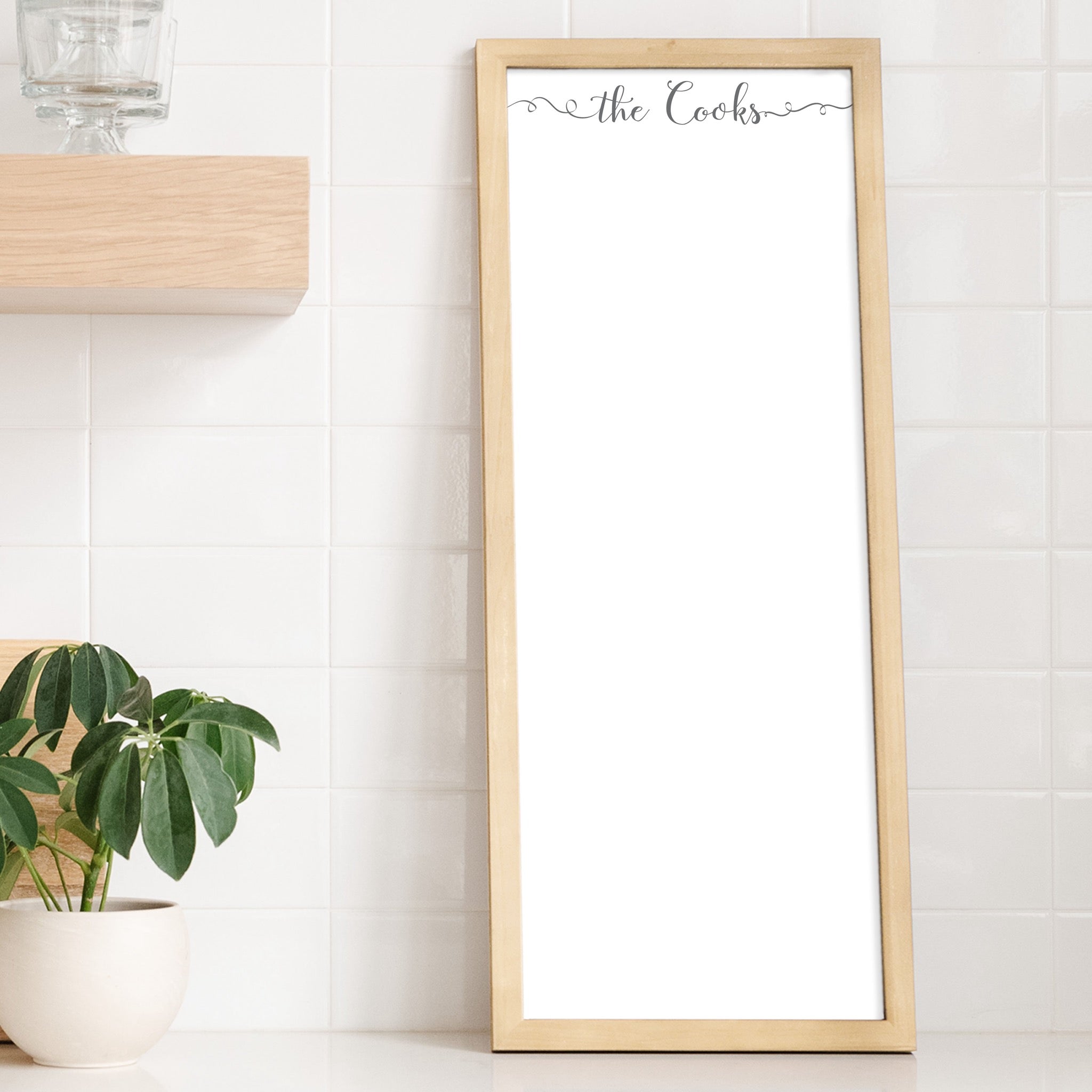 A framed whiteboard calendar with a two month design format hanging on the wall