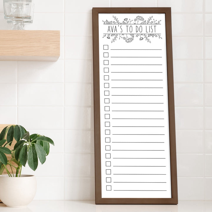 A framed whiteboard to do list hanging on the wall