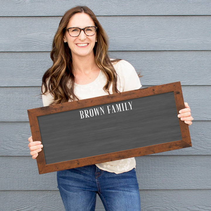 A framed dry-erase chalkboard calendar with a two month design format hanging on the wall
