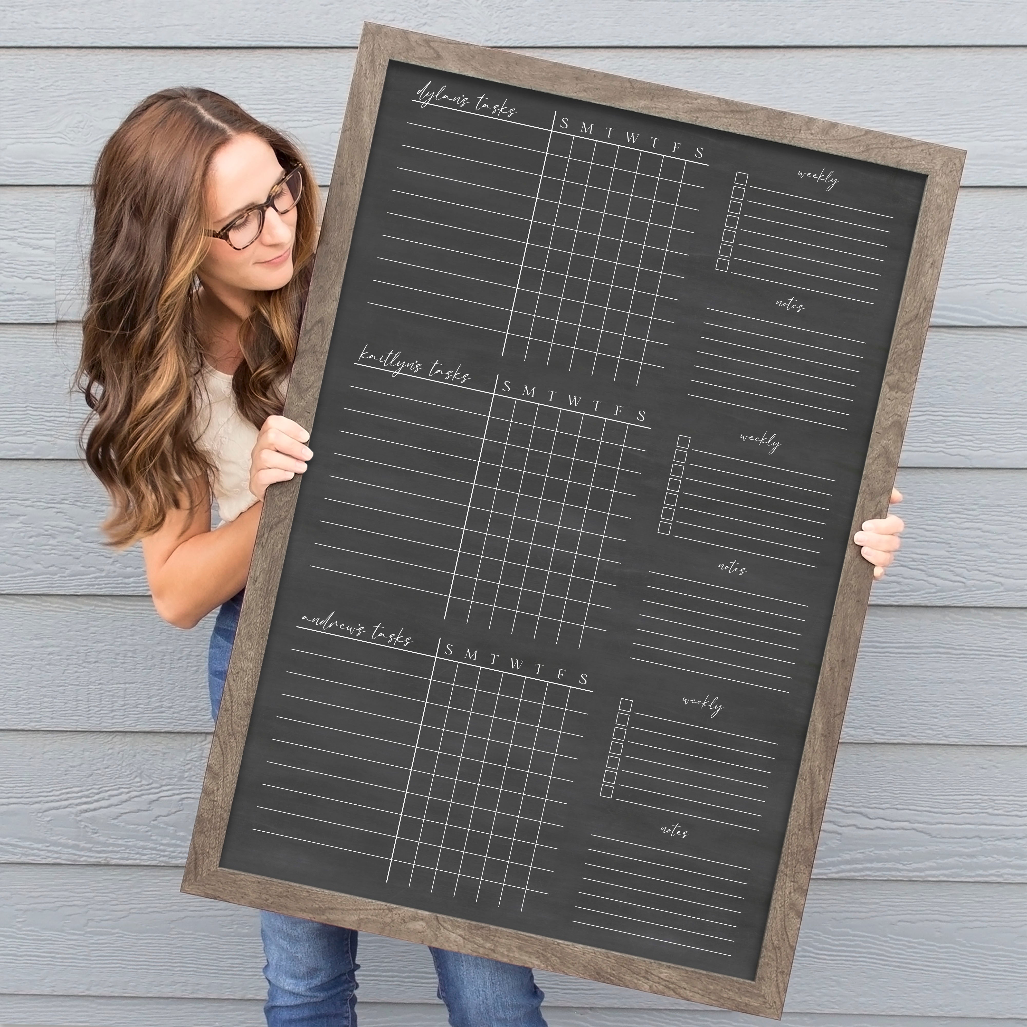 A framed dry-erase chore chart with a chalkboard look hanging on the wall