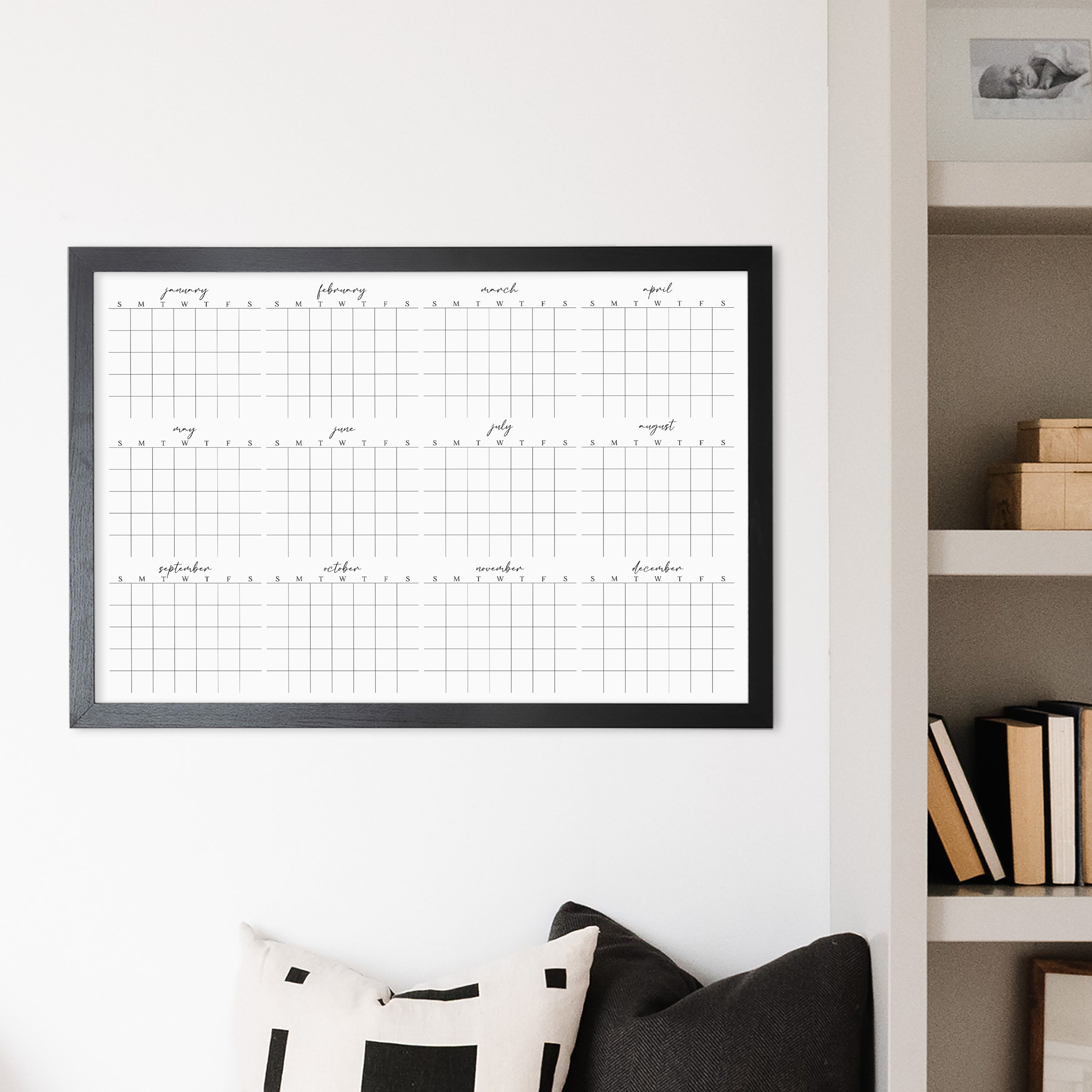 A framed whiteboard yearly calendar hanging up on the wall