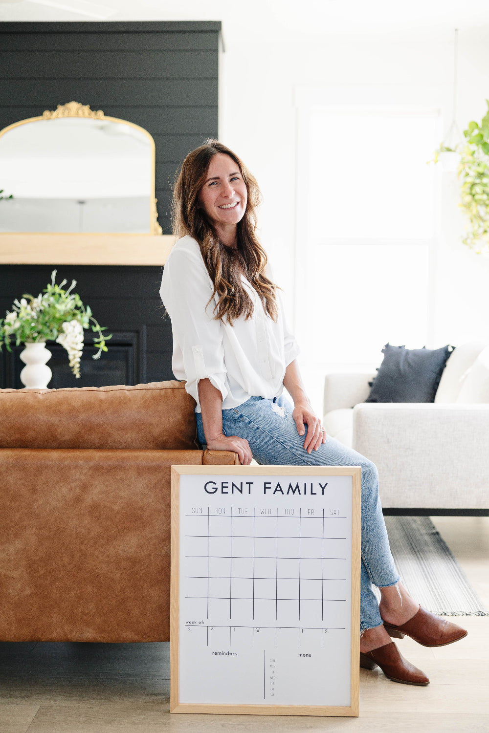 Woman holding a custom dry-erase framed calendar in a living room.