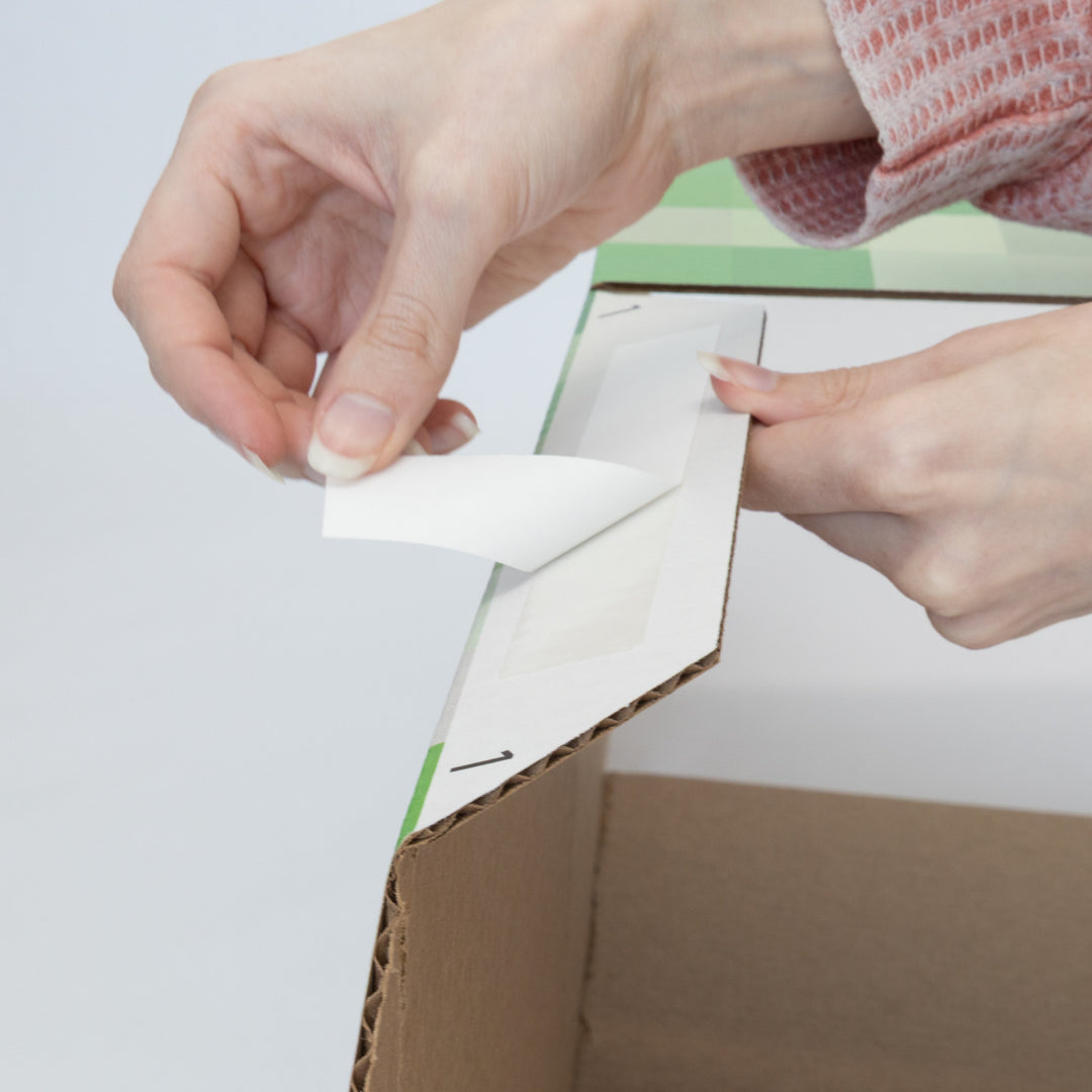A hand peeling off the tape backing on a pixel cube.