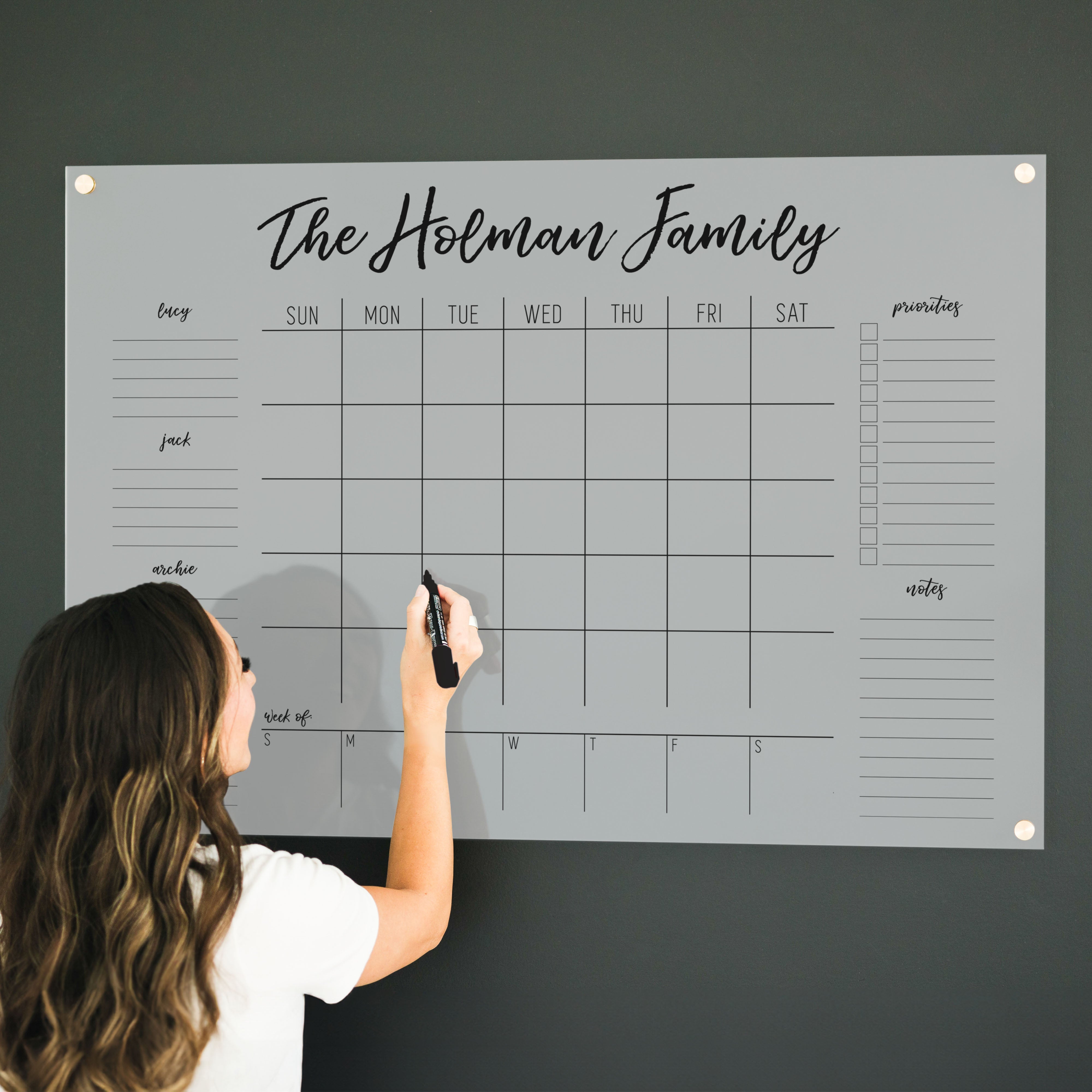 A Dry-erase calendar with a monthly and weekly format made of acrylic hanging on the wall
