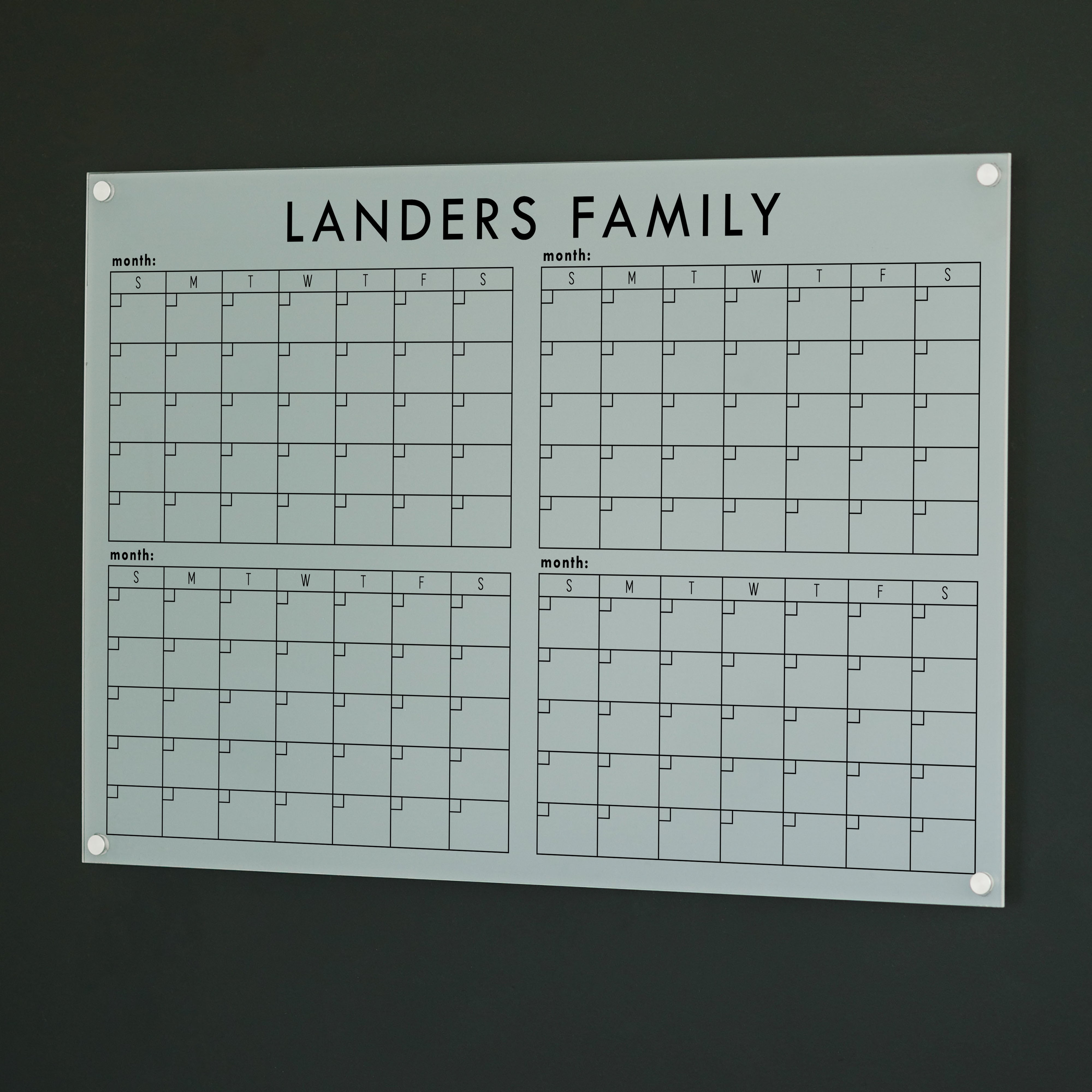 A dry-erase four month calendar made of acrylic hanging on the wall