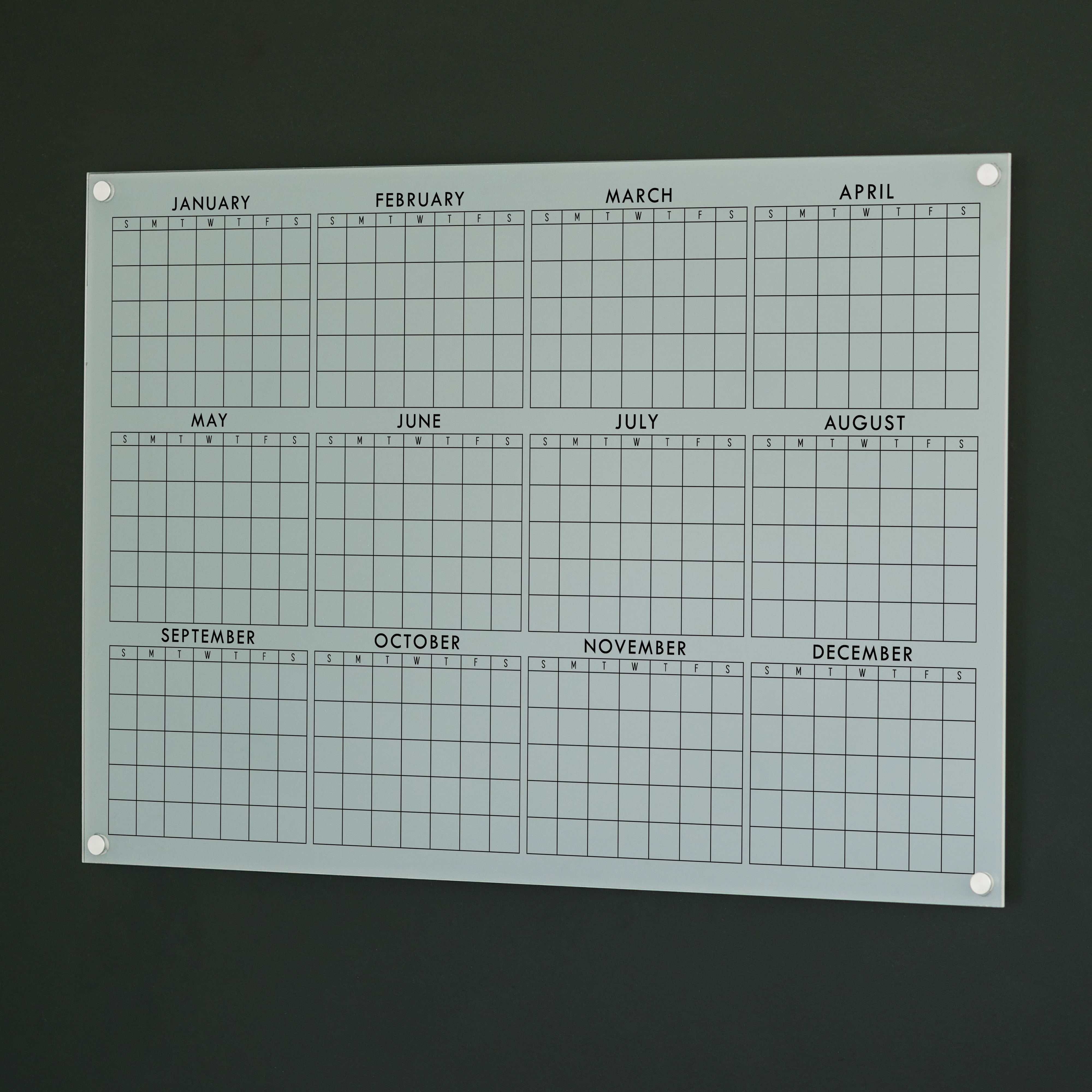A dry-erase yearly calendar made of acrylic hanging up on the wall