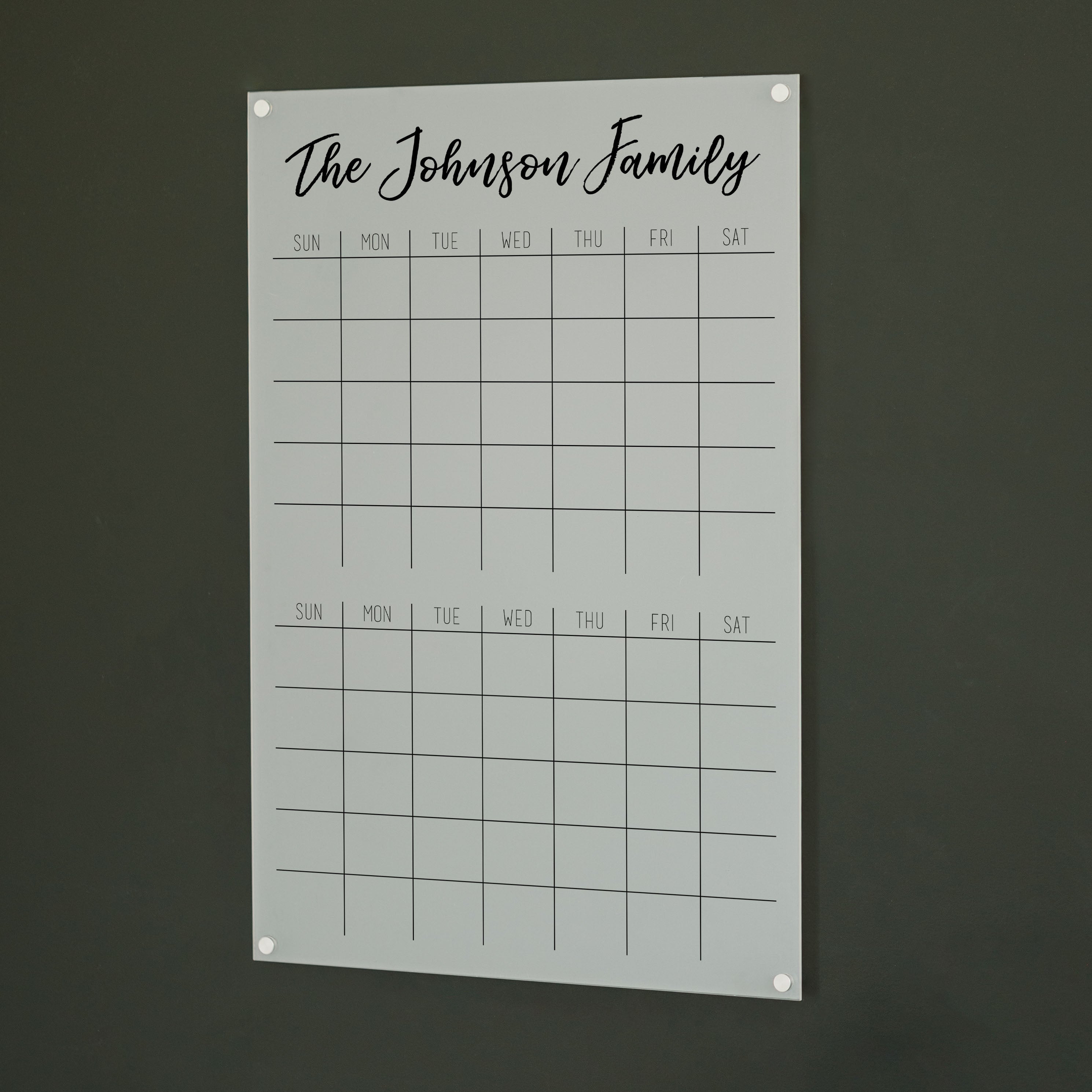 A Dry-erase acrylic calendar with a two month design format hanging on the wall