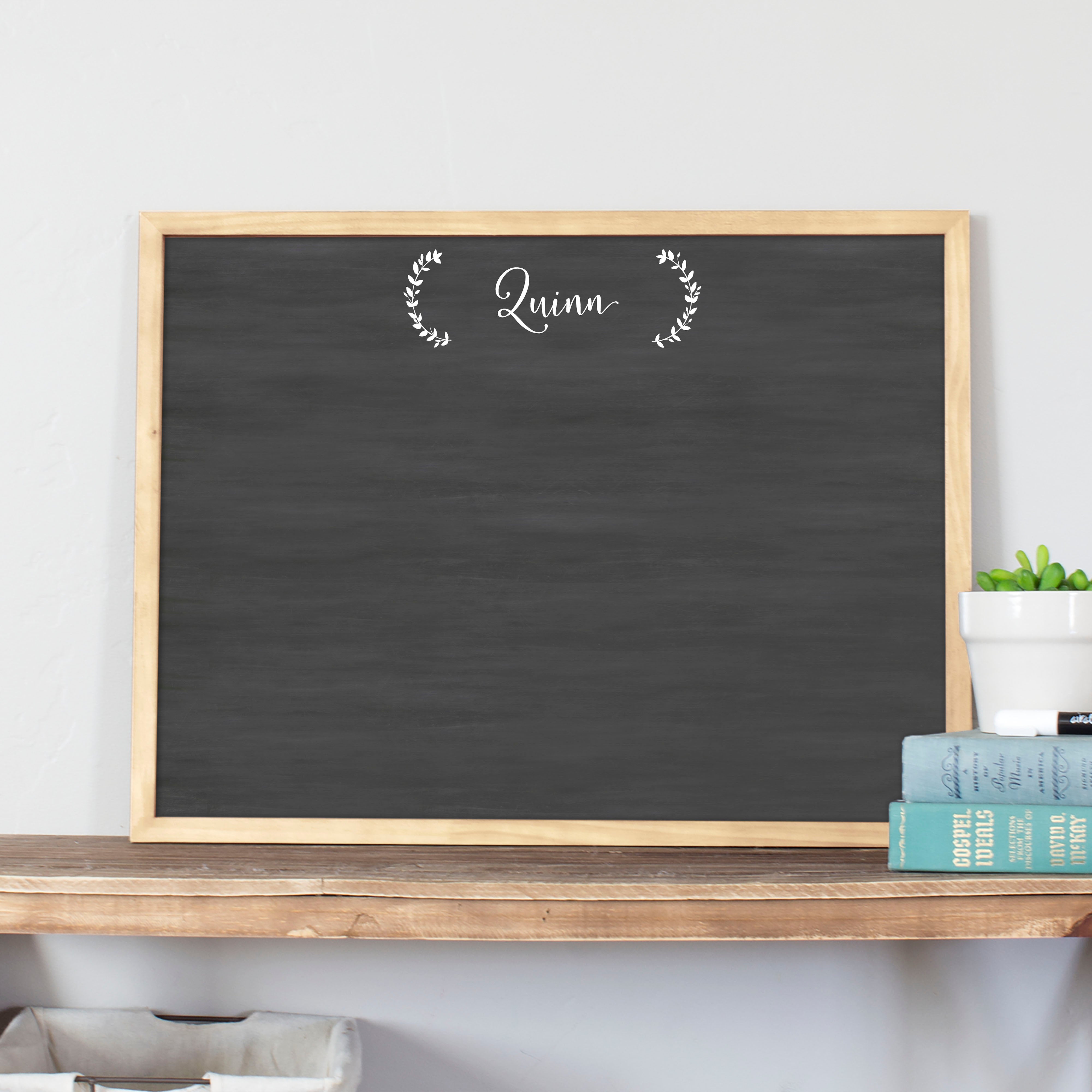 A framed dry-erase chalkboard calendar with a two month design format hanging on the wall