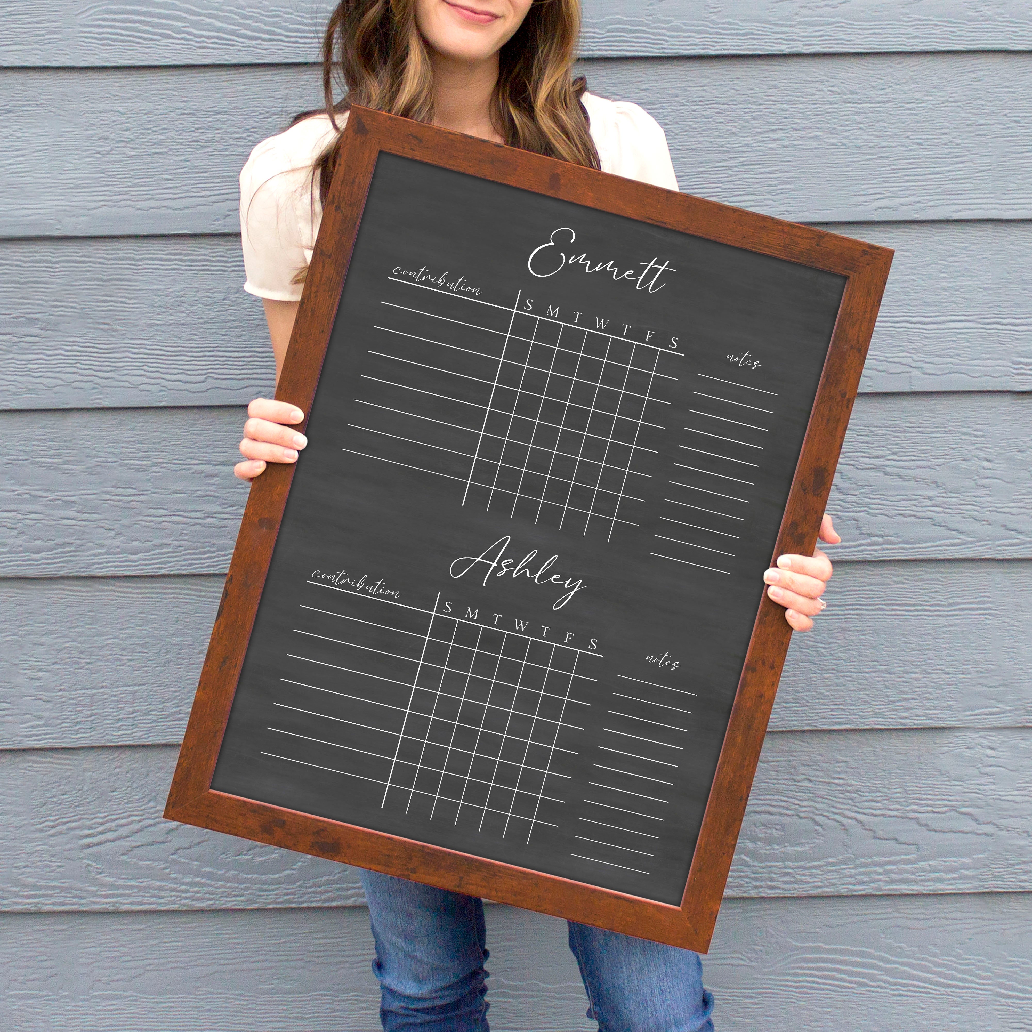 A framed dry-erase chore chart with a chalkboard look hanging on the wall