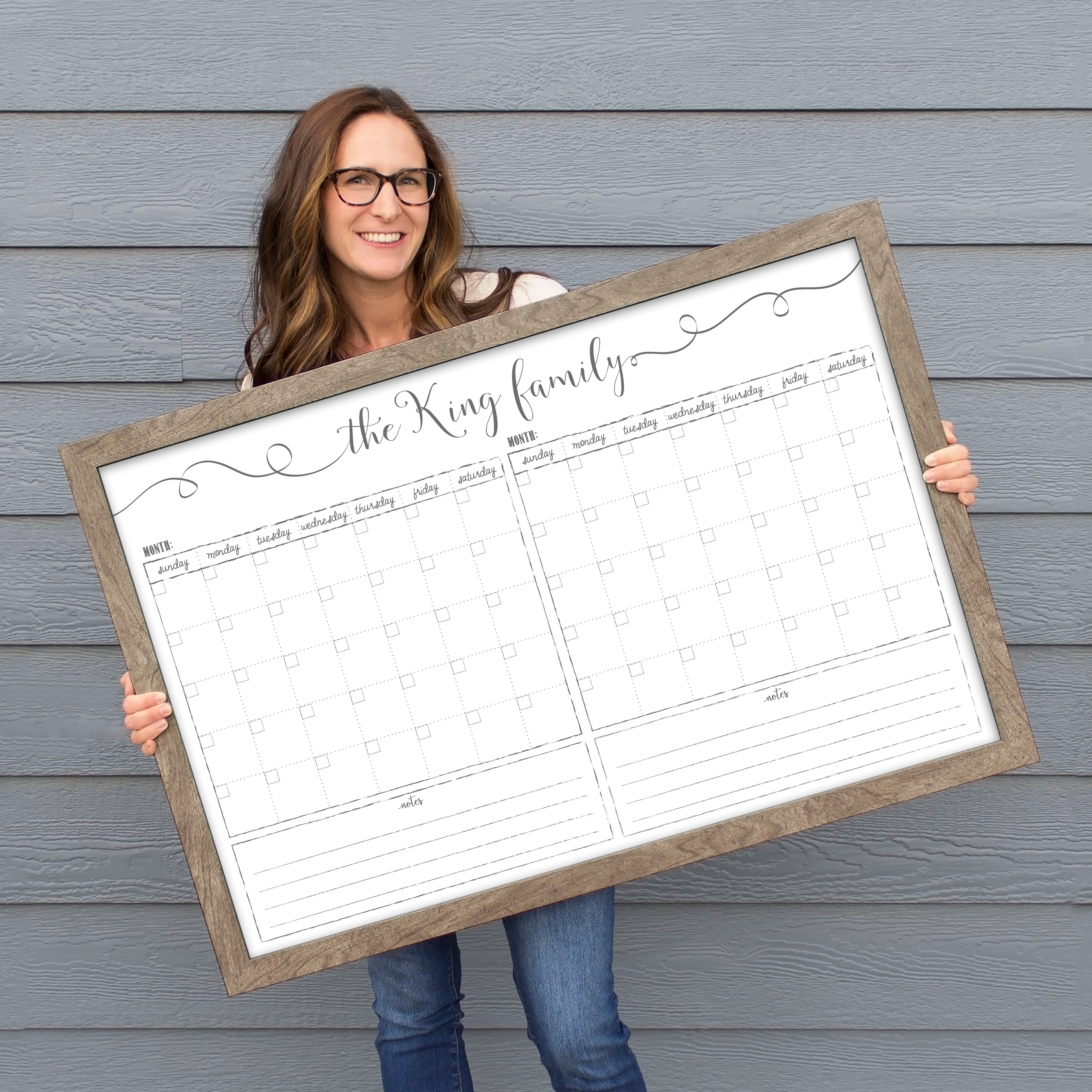 A framed whiteboard calendar with a two month design format hanging on the wall