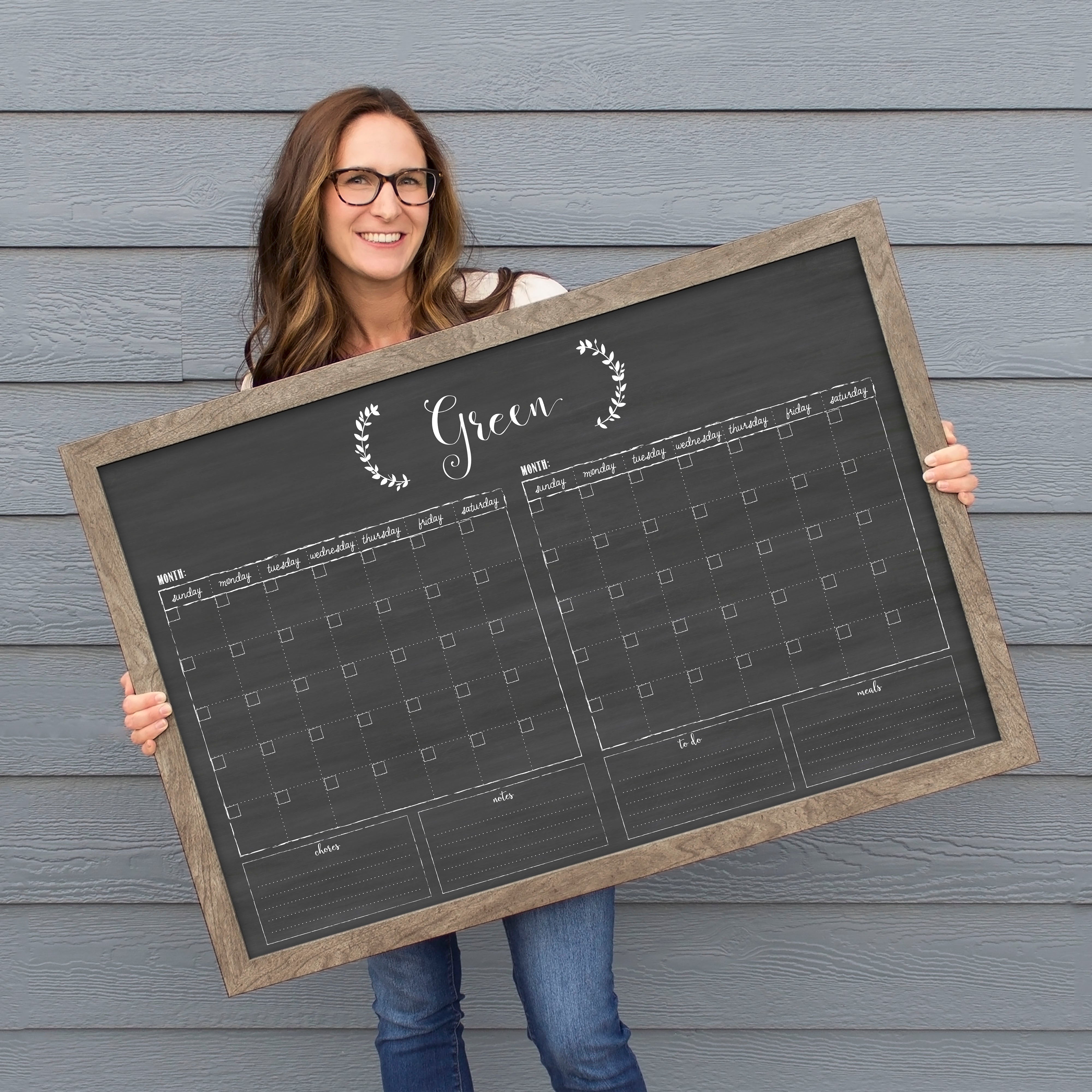 A framed chalkboard dry-erase calendar with a two month design format hanging on the wall