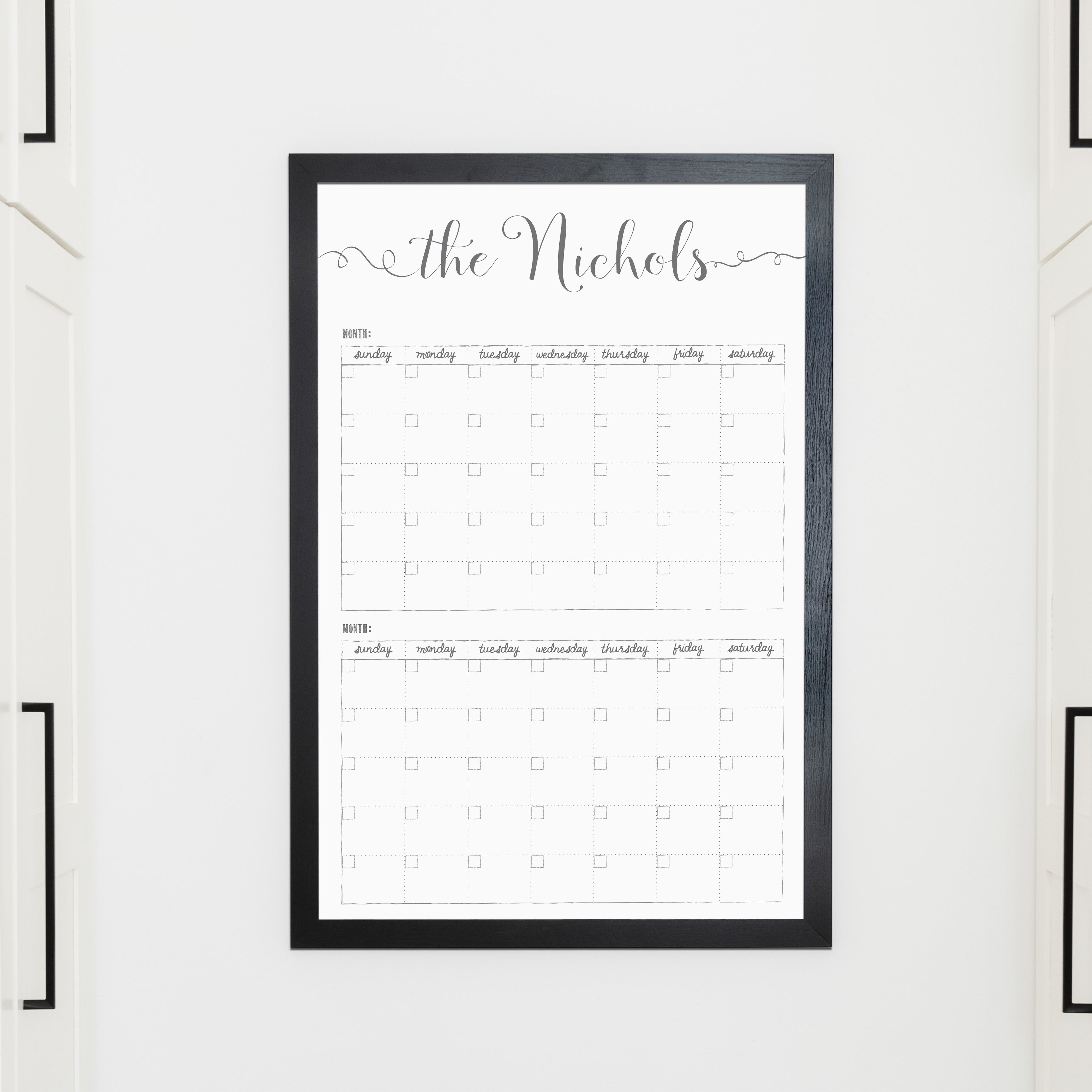 A framed whiteboard calendar with a two month design format hanging on the wall