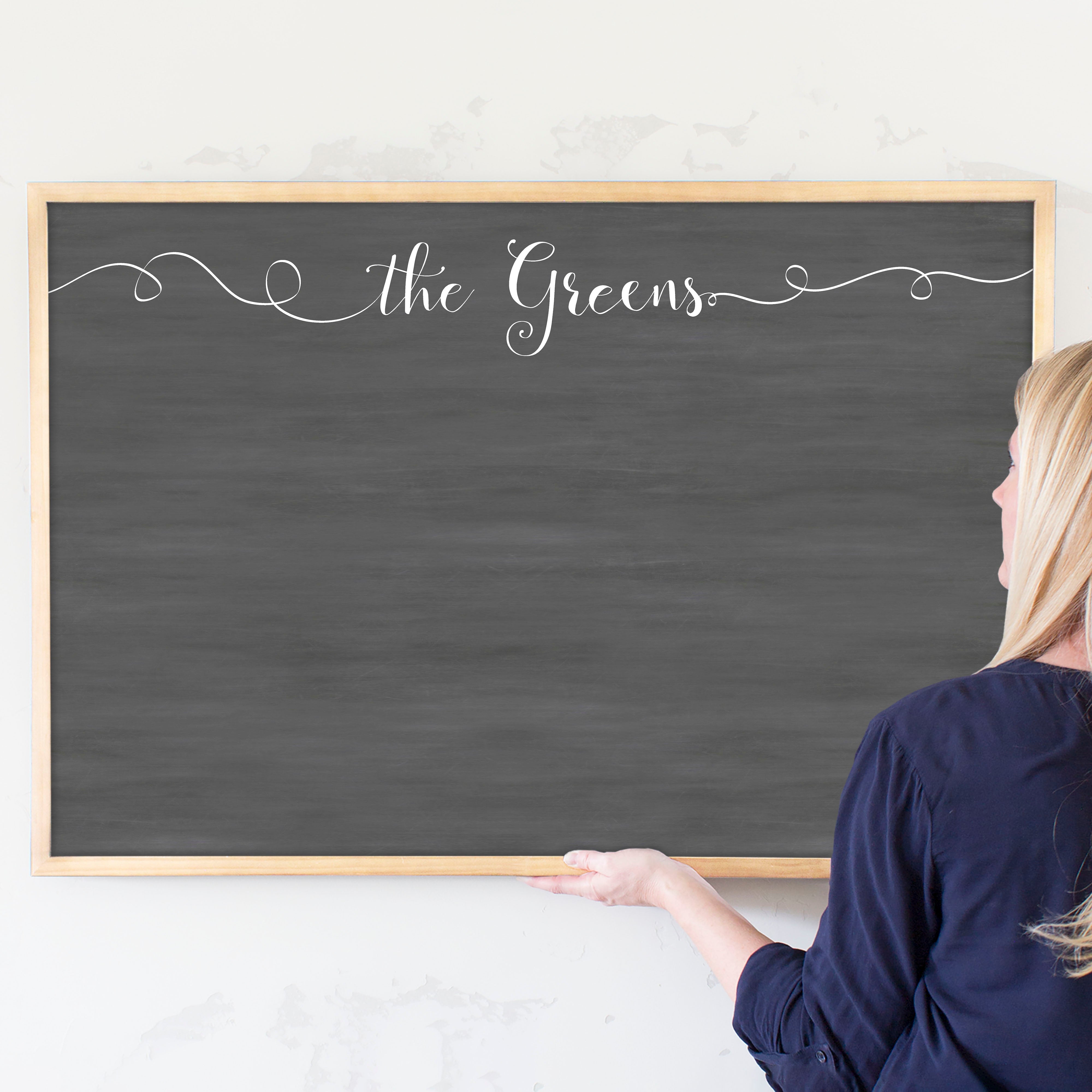 A framed dry-erase chalkboard calendar with a two month design format hanging on the wall