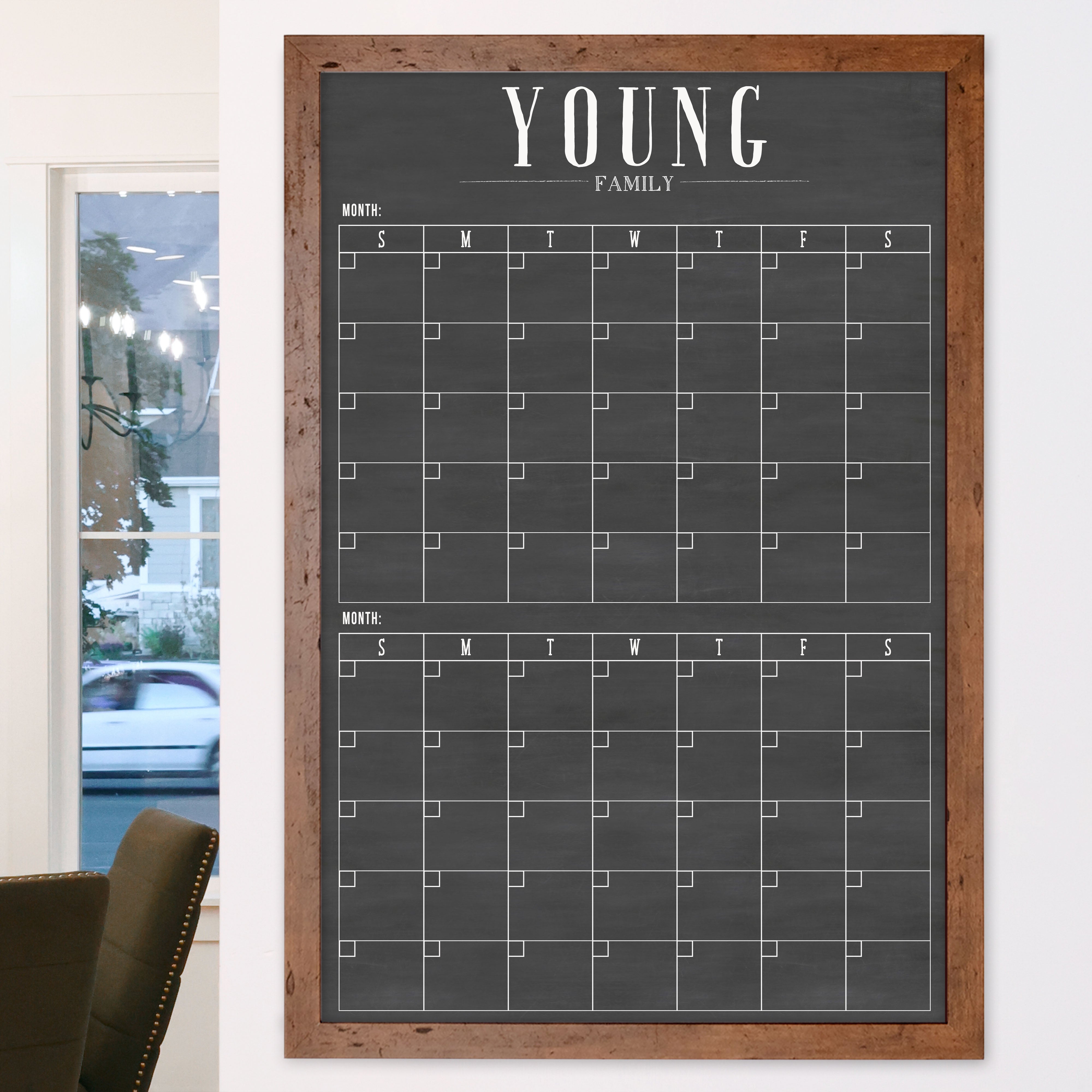 A framed chalkboard dry-erase calendar with a two month design format hanging on the wall