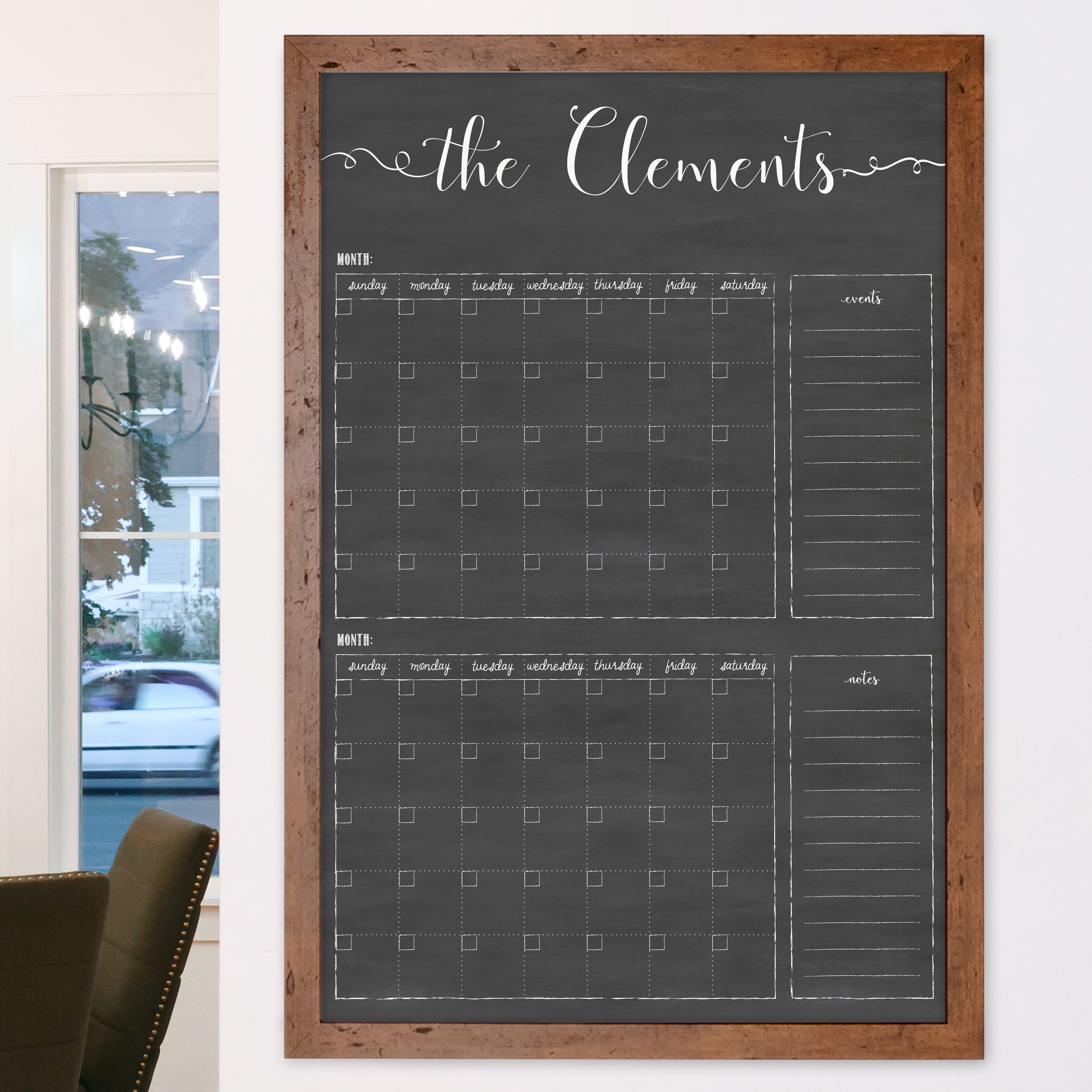 A framed chalkboard dry-erase calendar with a two month design format hanging on the wall