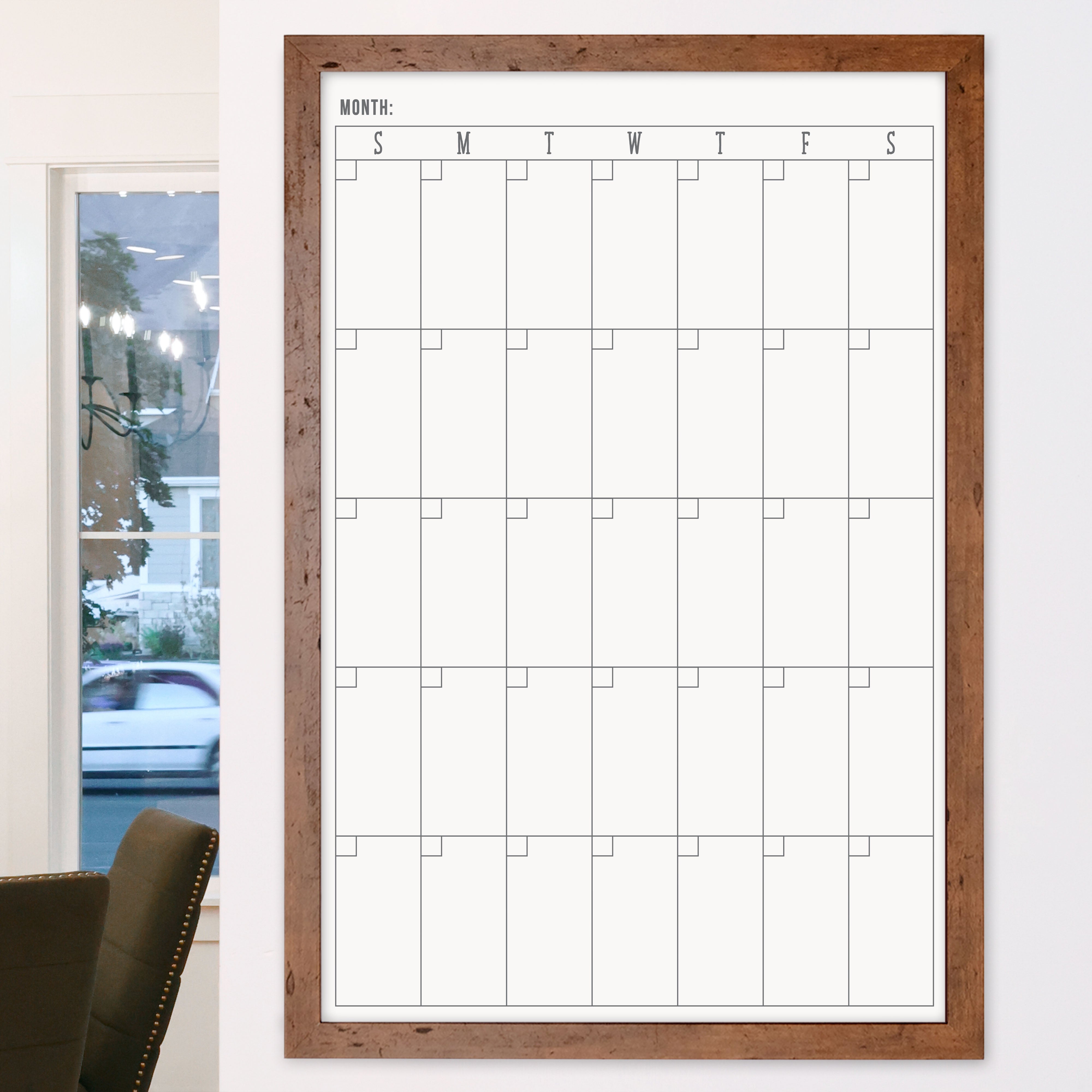 A framed whiteboard monthly calender hanging on the wall