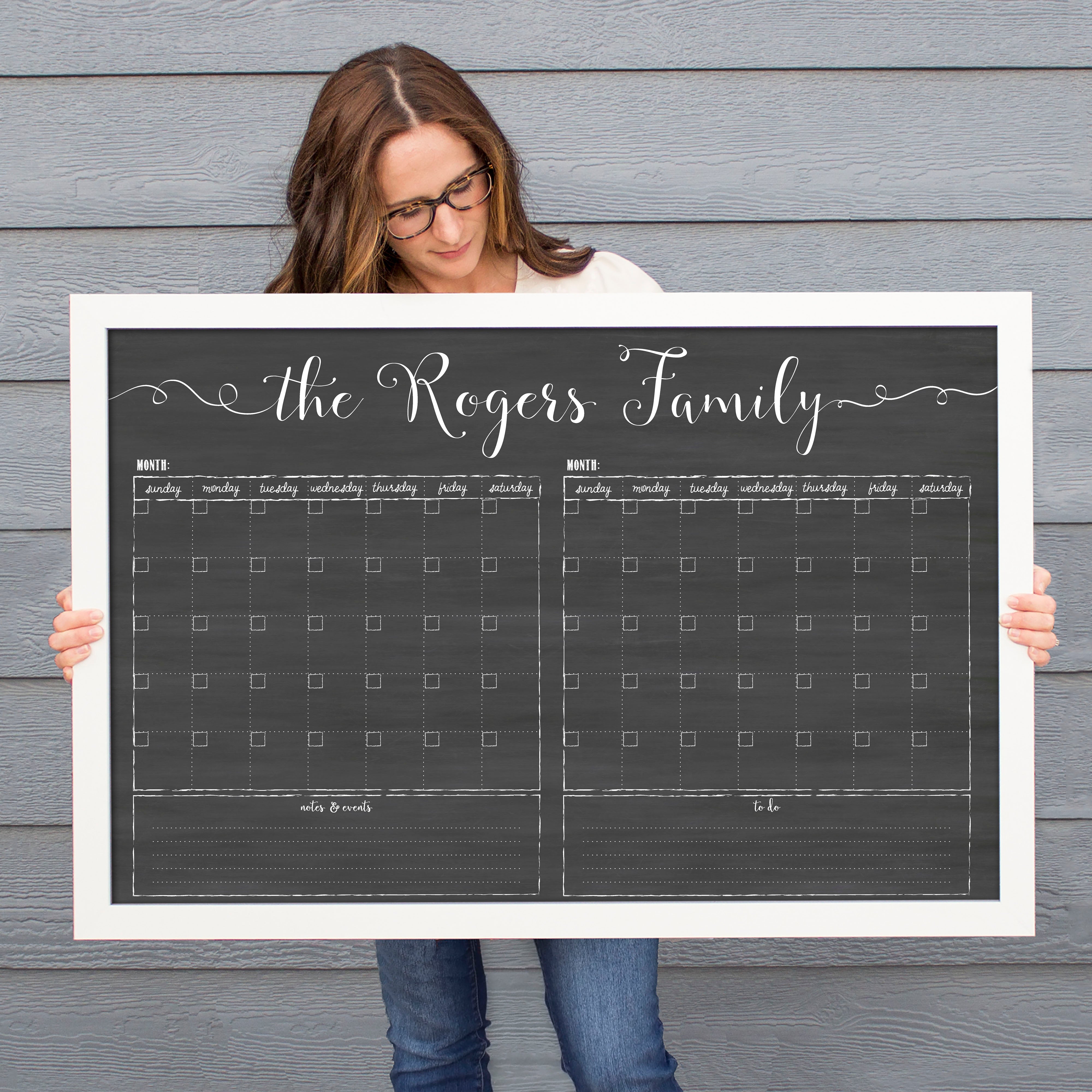 A framed chalkboard dry-erase calendar with a two month design format hanging on the wall