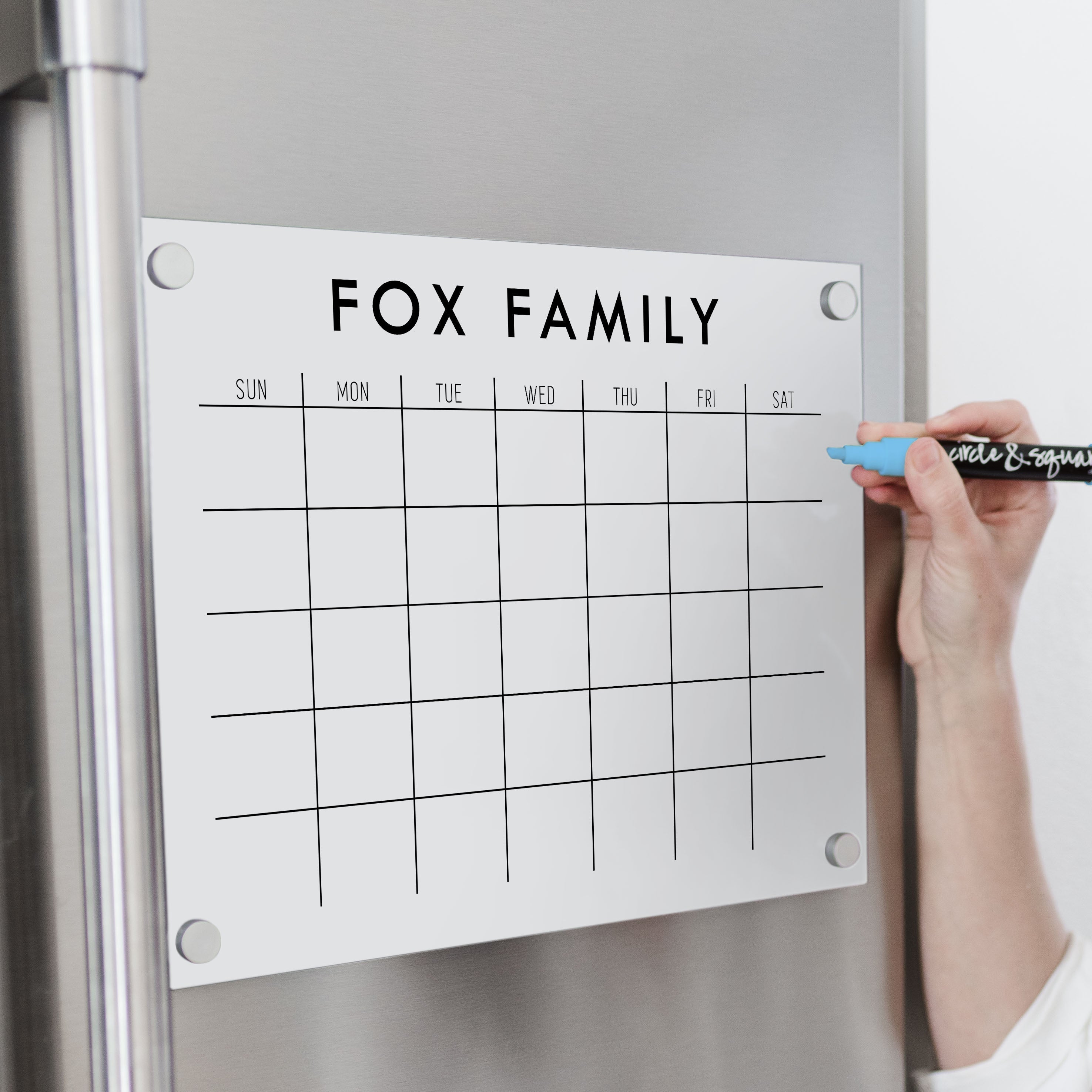 A Dry-erase monthly calender made of acrylic hanging on the fridge