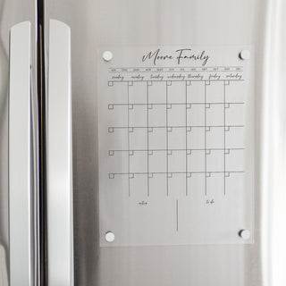A Dry-erase monthly calender made of acrylic hanging on the fridge