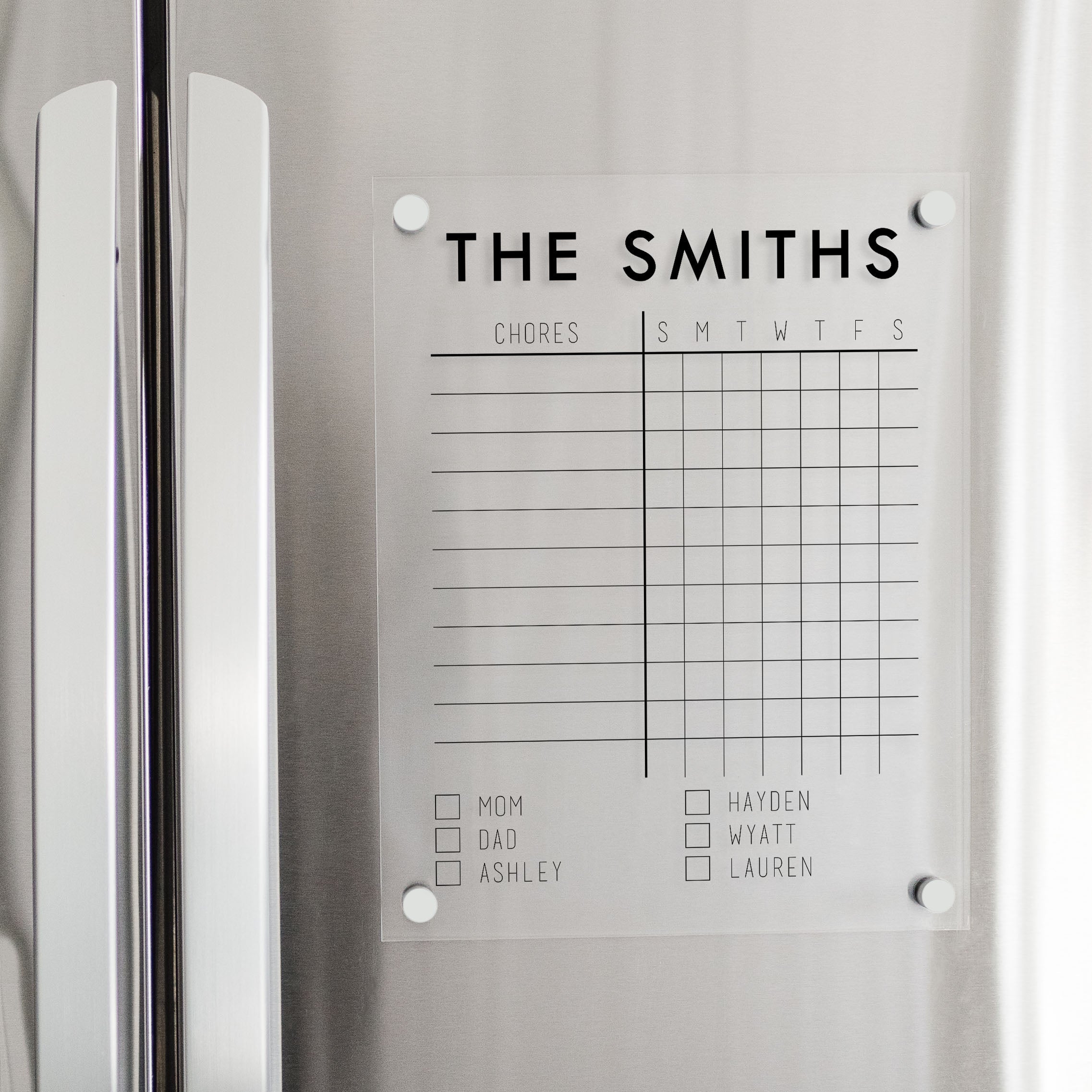 A Dry-erase acrylic chore chart hanging on the fridge