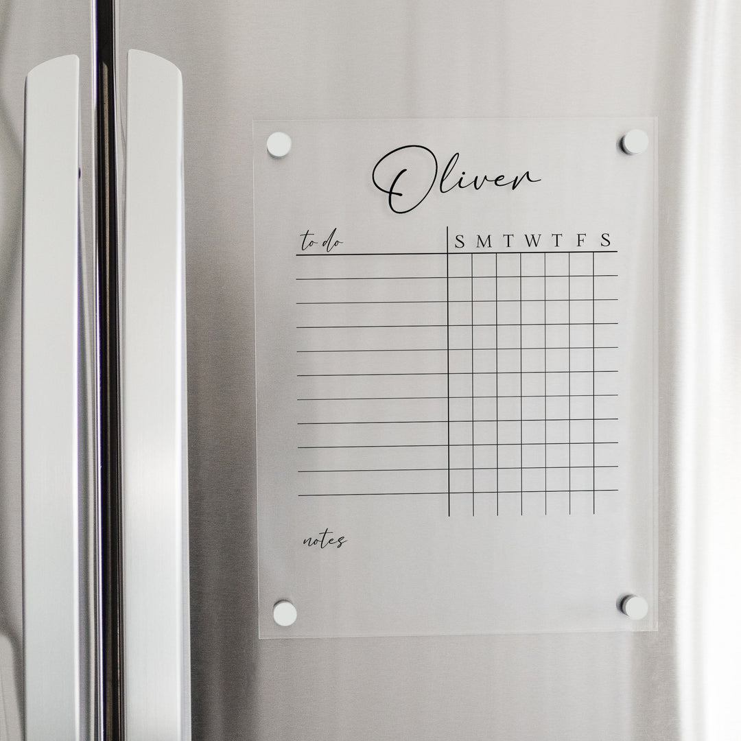 A Dry-erase acrylic chore chart hanging on the fridge