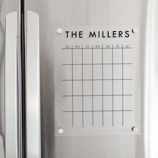 A Dry-erase monthly calender made of acrylic hanging on the fridge