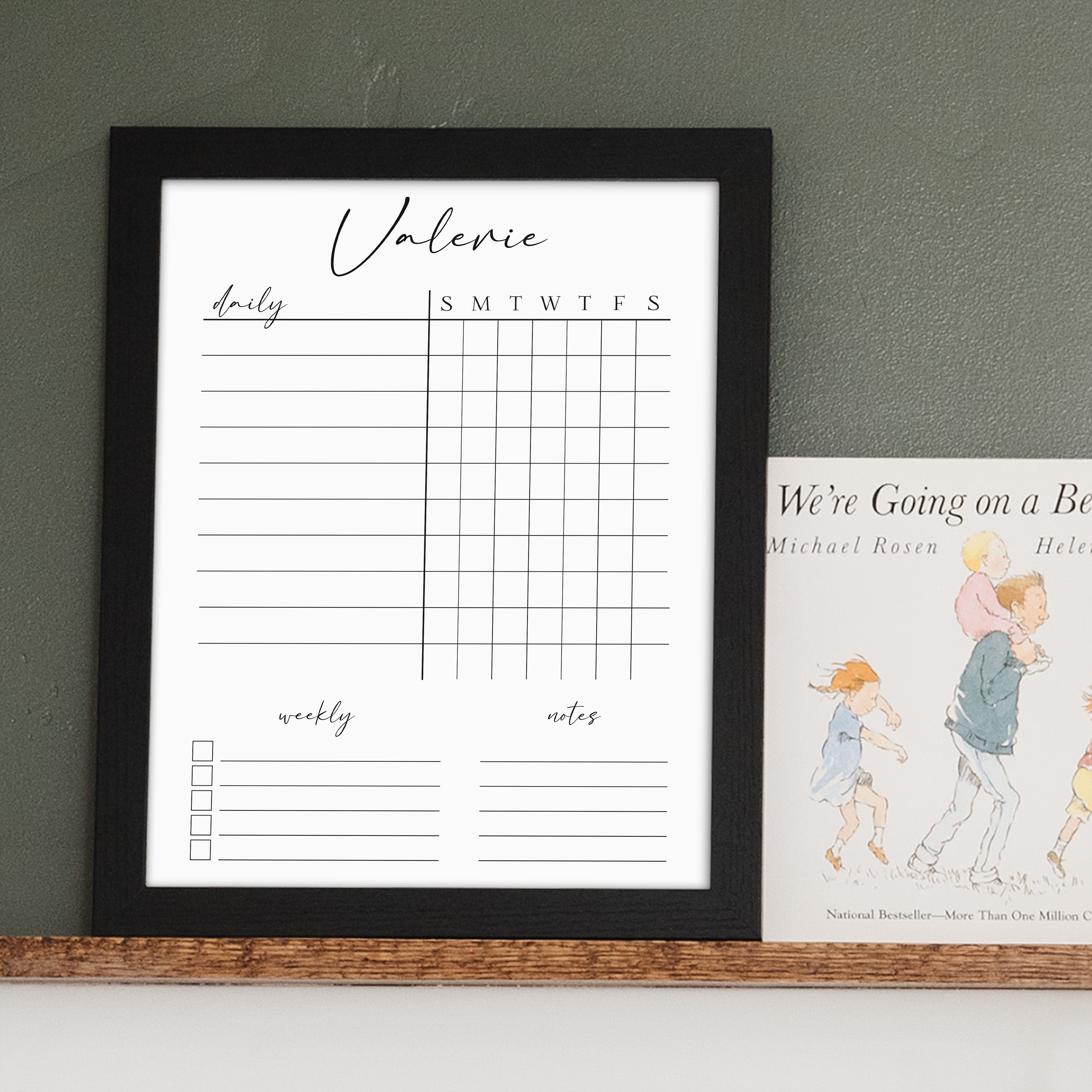 A framed whiteboard chore chart hanging on the wall