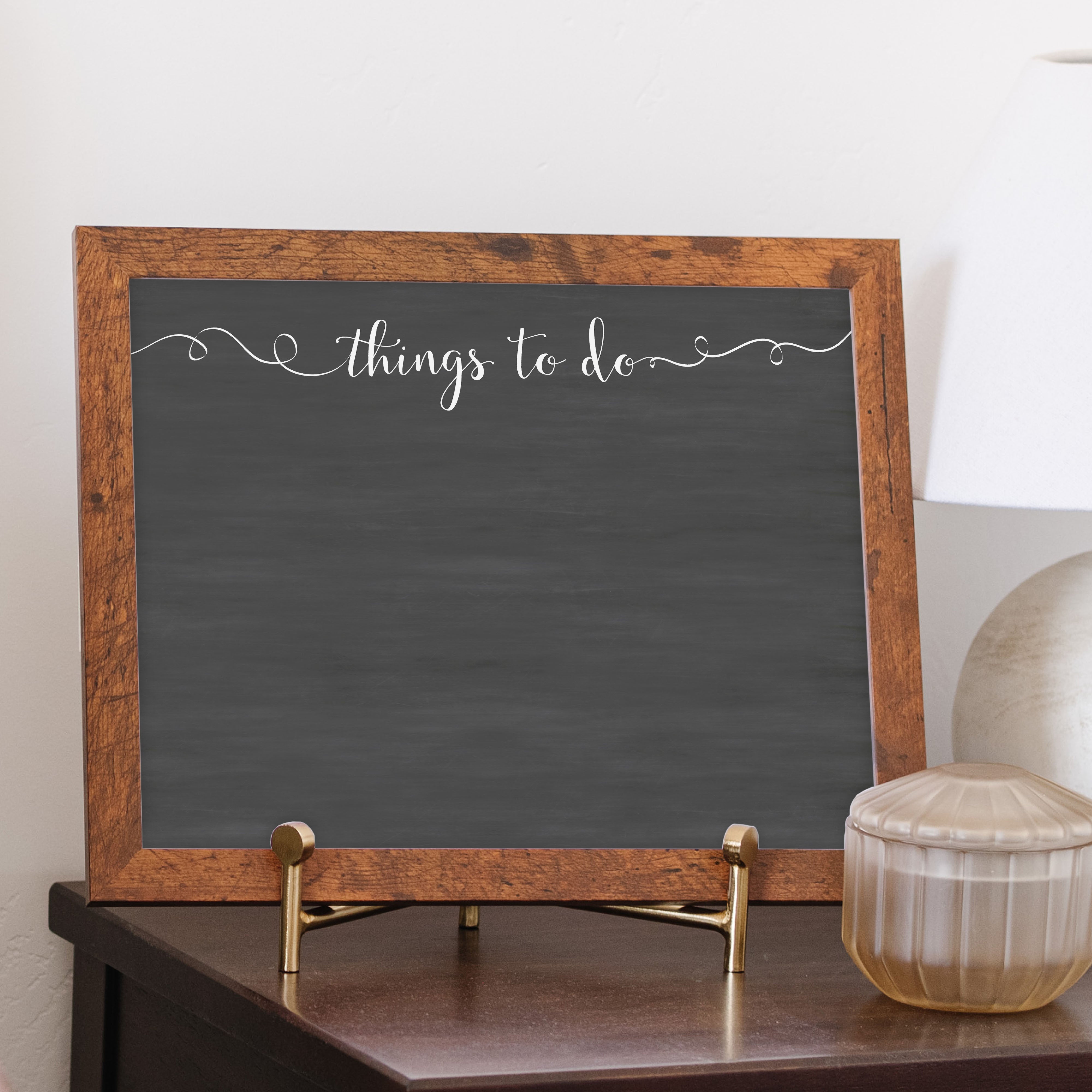 A framed dry-erase chalkboard calendar with a two month design format hanging on the wall