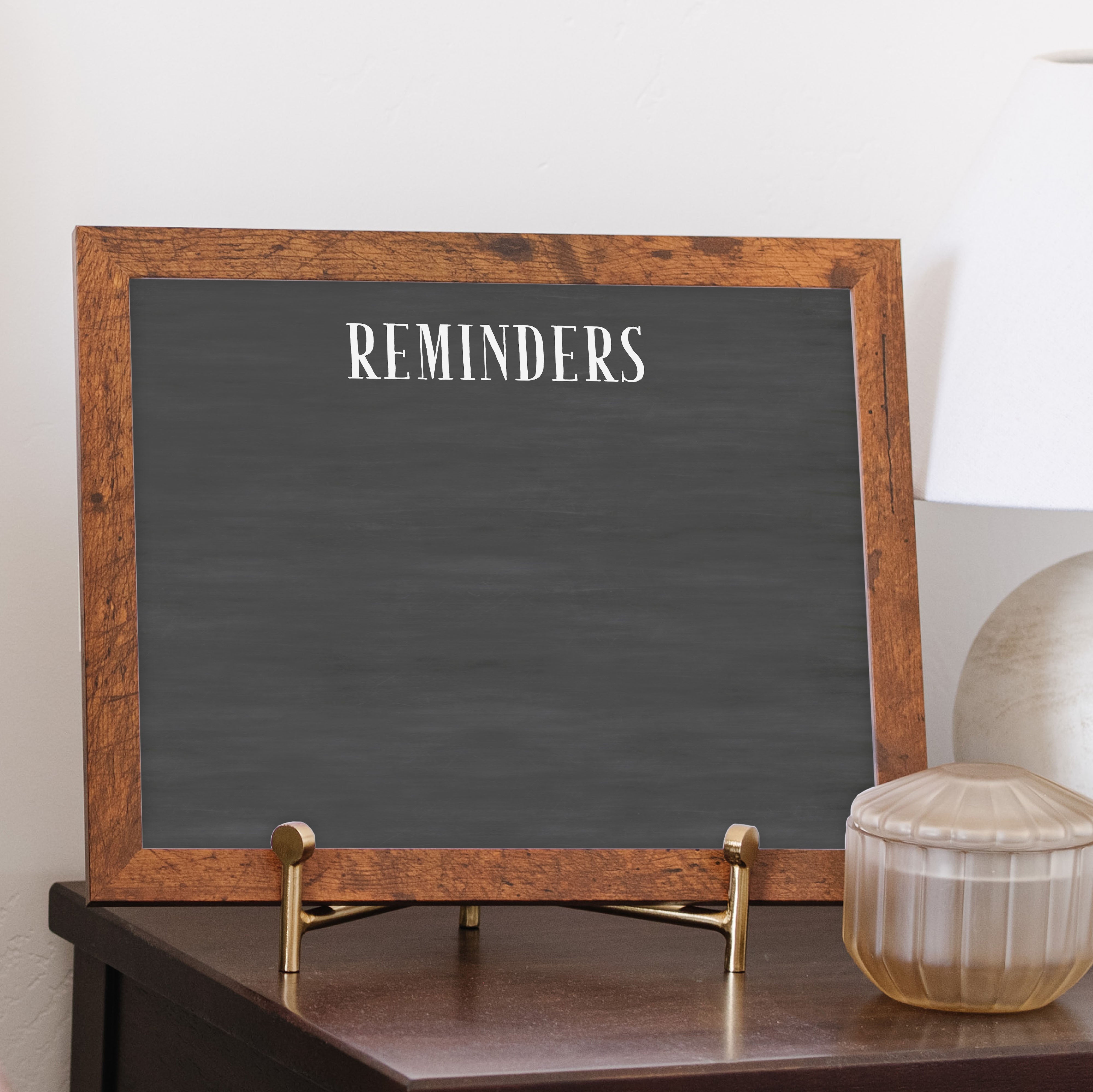 A framed dry-erase chalkboard calendar with a two month design format hanging on the wall