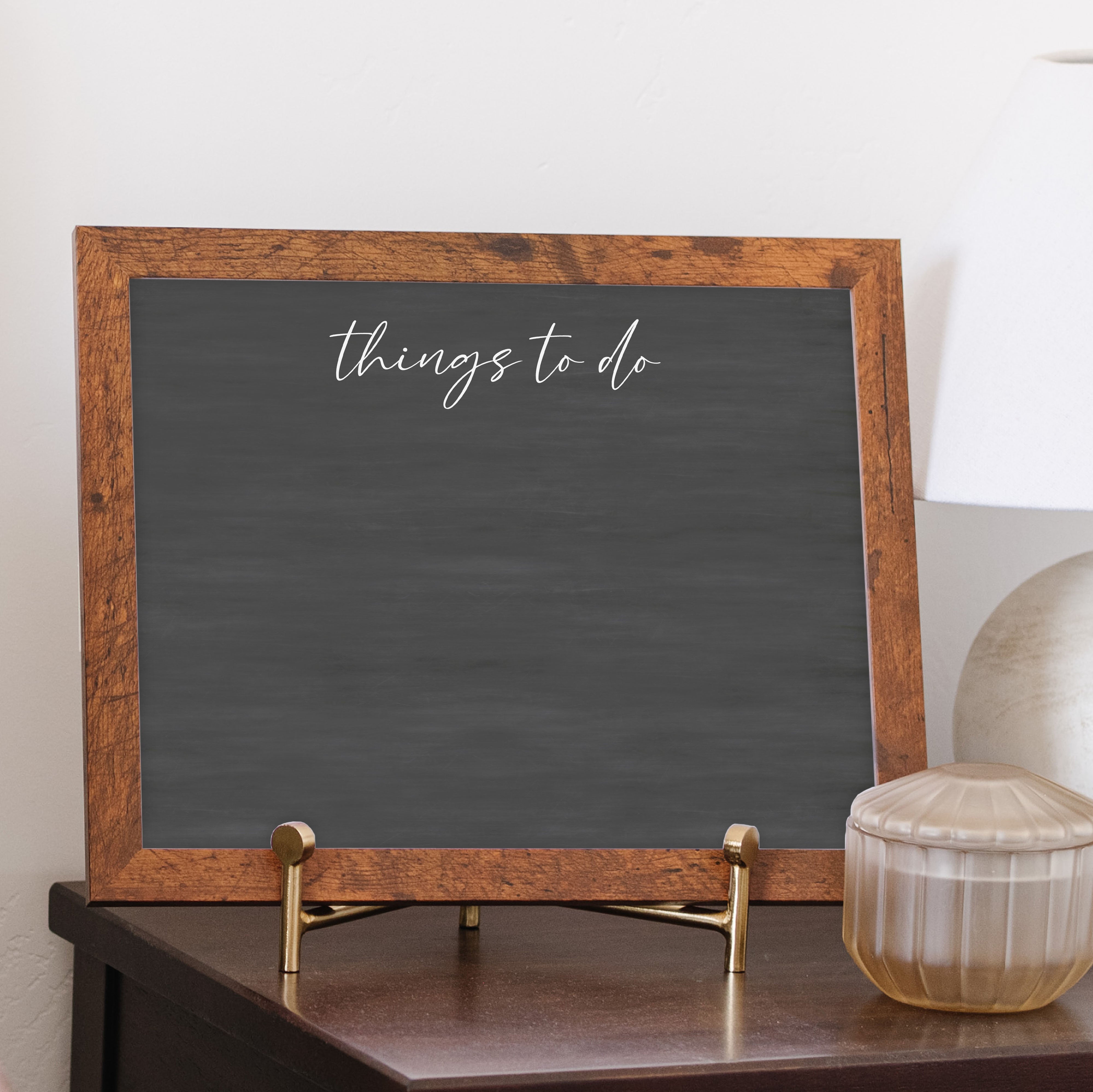 A framed dry-erase chalkboard calendar with a two month design format hanging on the wall