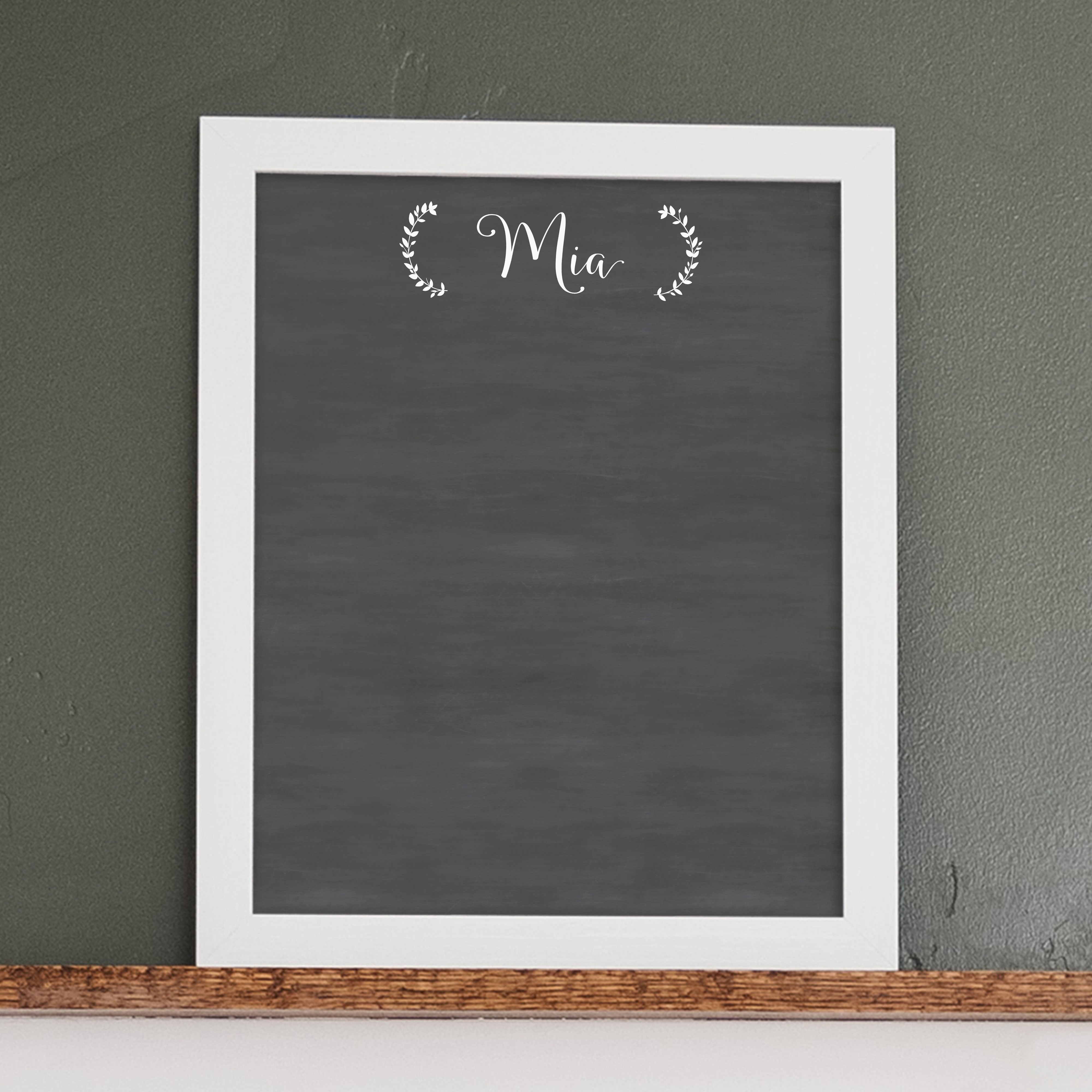 A framed dry-erase chalkboard calendar with a two month design format hanging on the wall