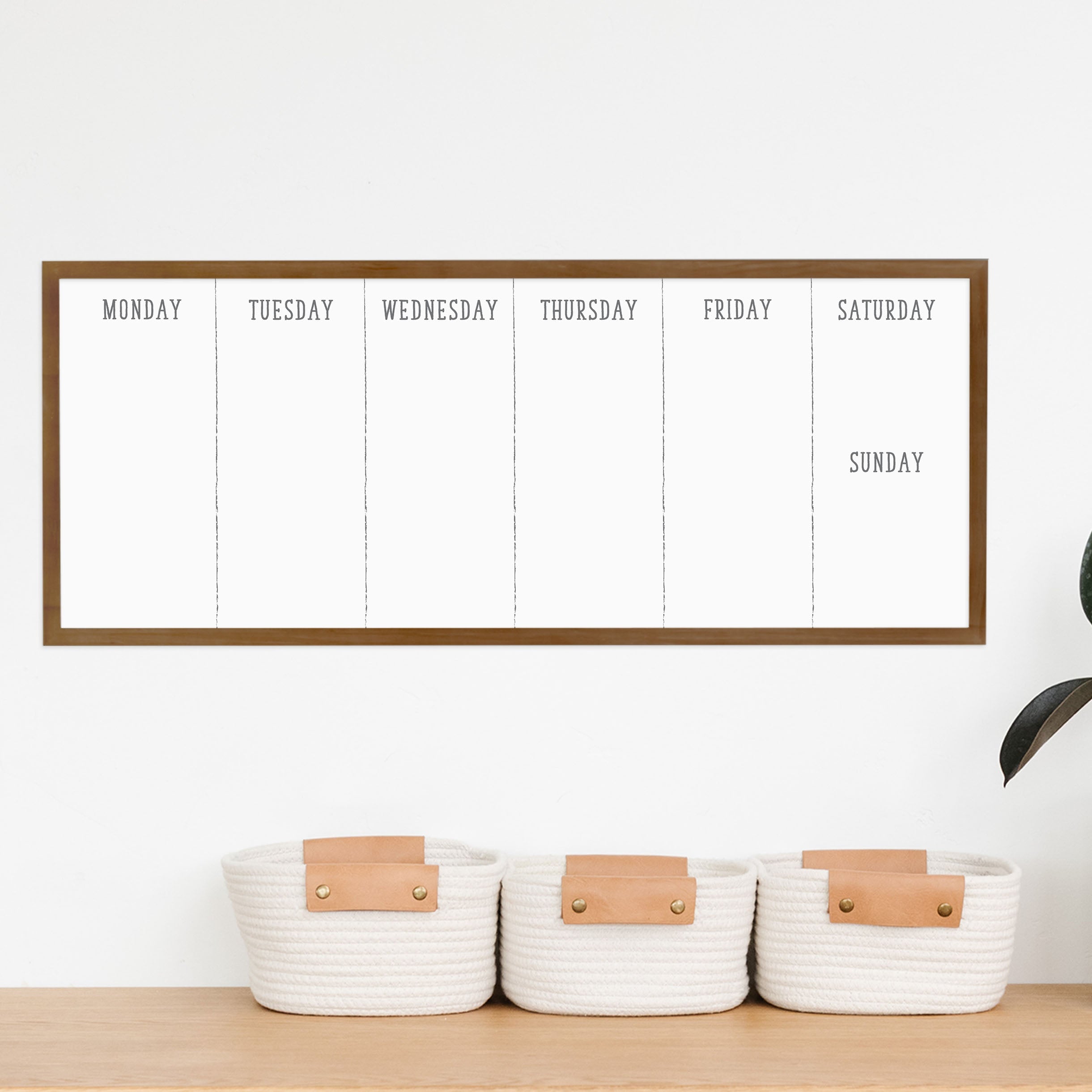 A framed slim whiteboard weekly calender hanging on the wall