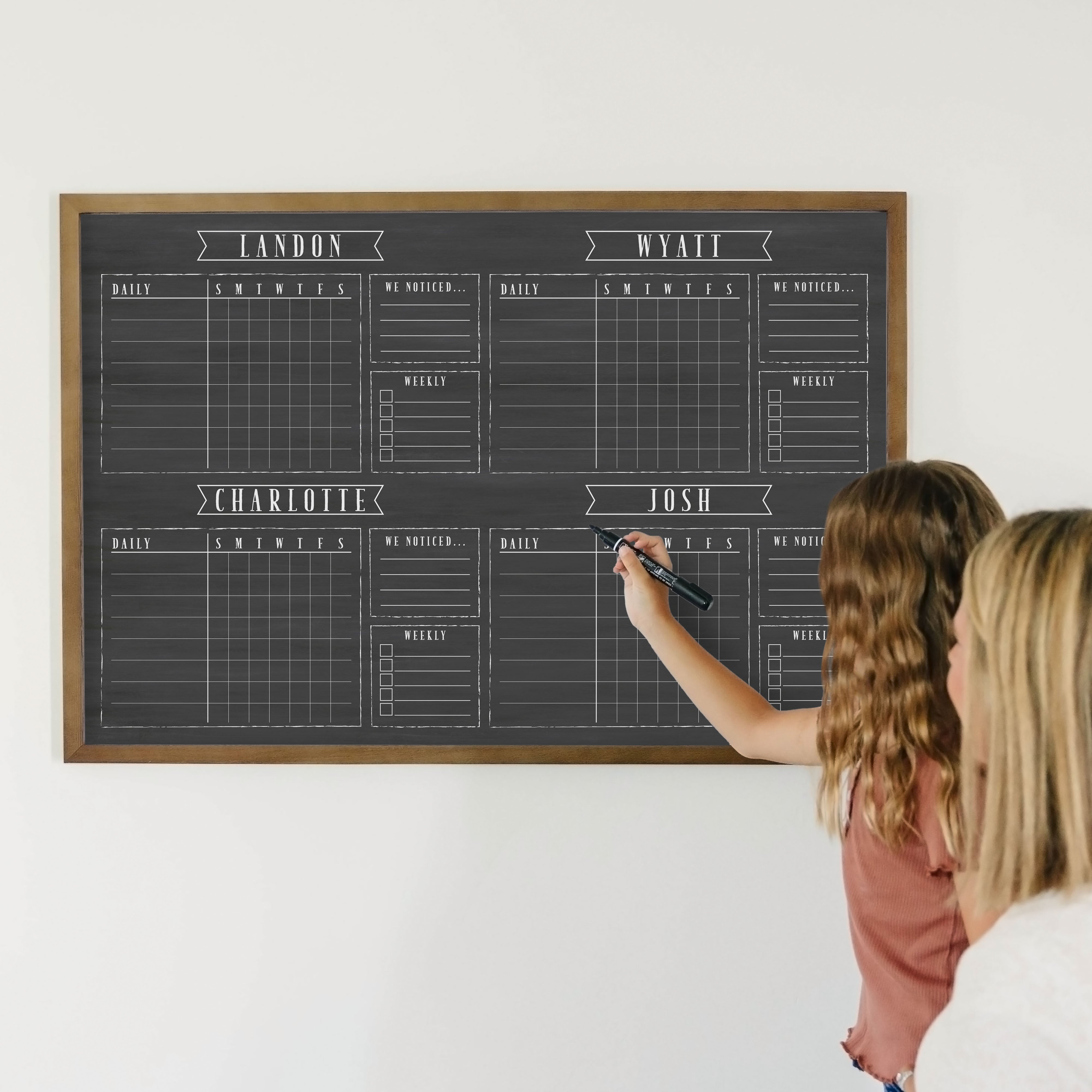 A framed dry-erase chore chart with a chalkboard look hanging on the wall