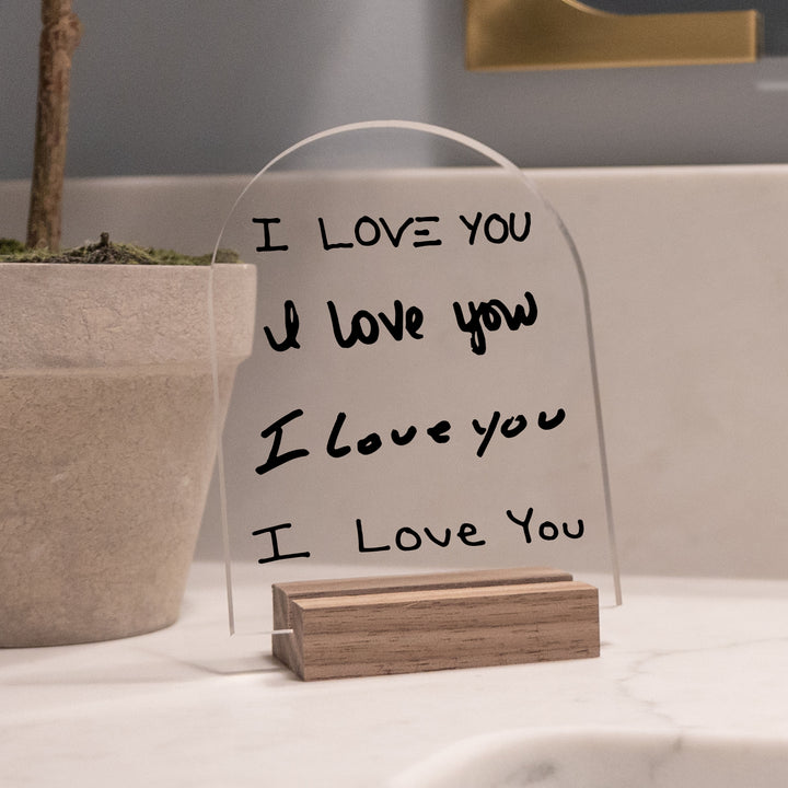 A clear acrylic 3x4 arch sign with "I love you" written in different handwriting