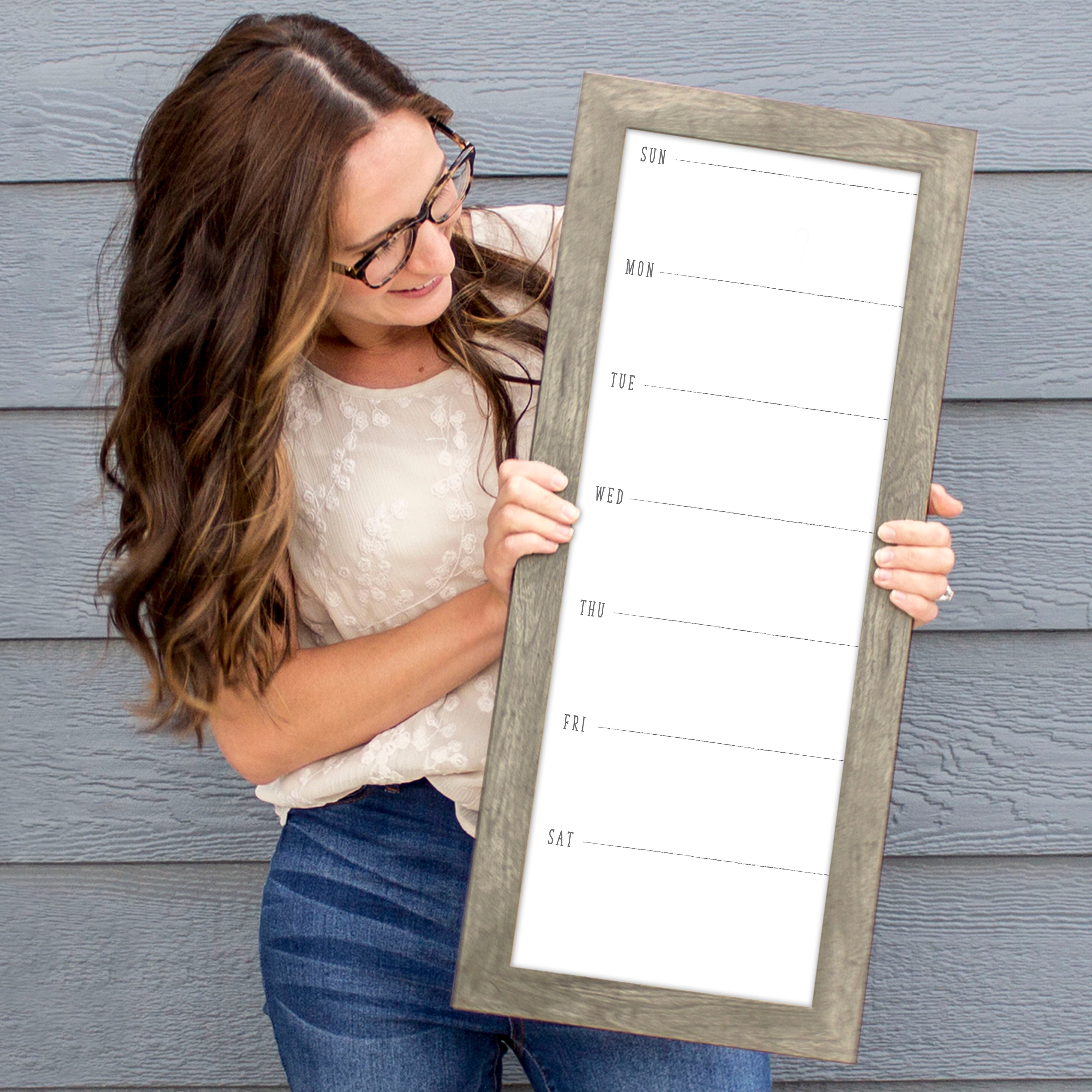 A framed slim whiteboard weekly calender hanging on the wall