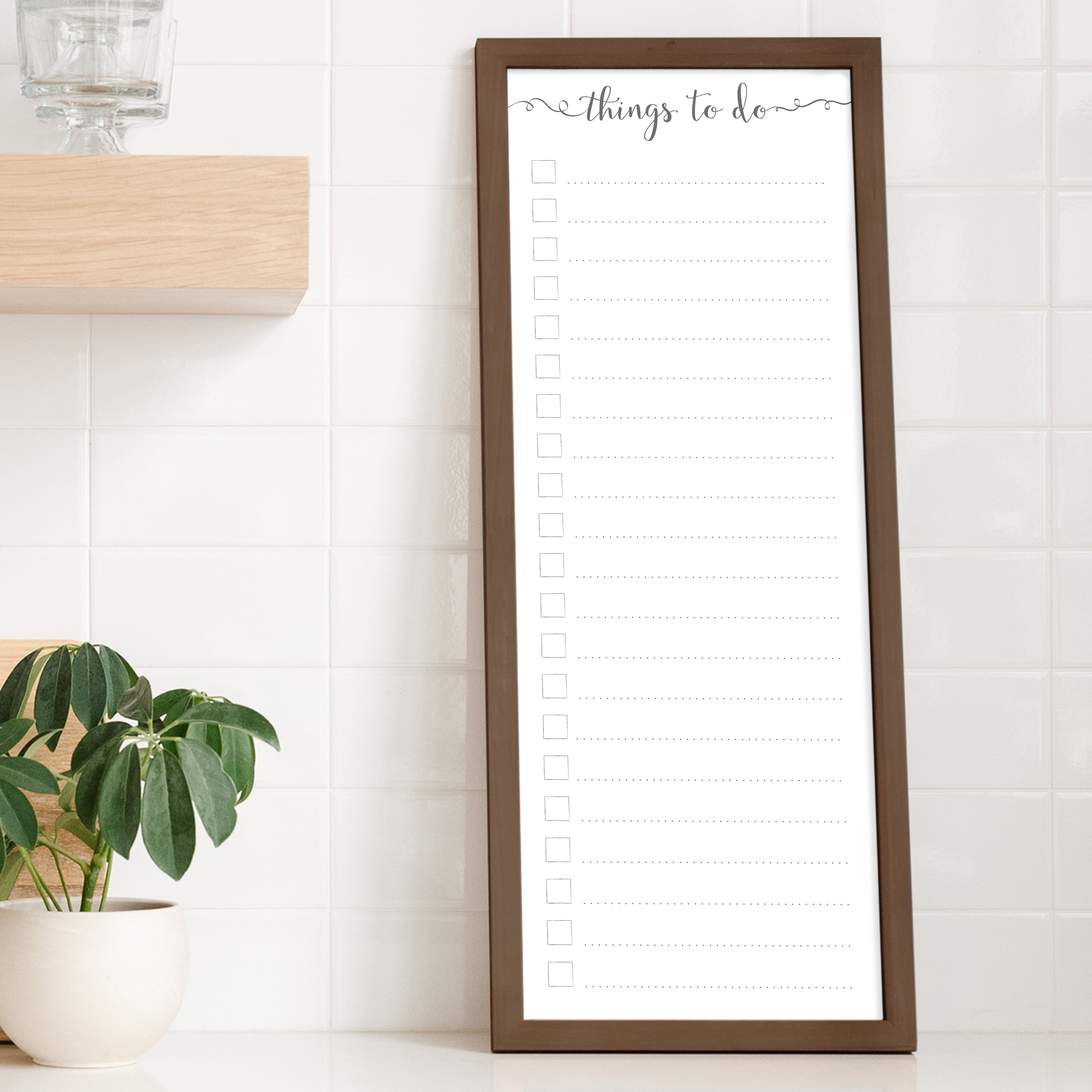 A framed whiteboard to do list hanging on the wall