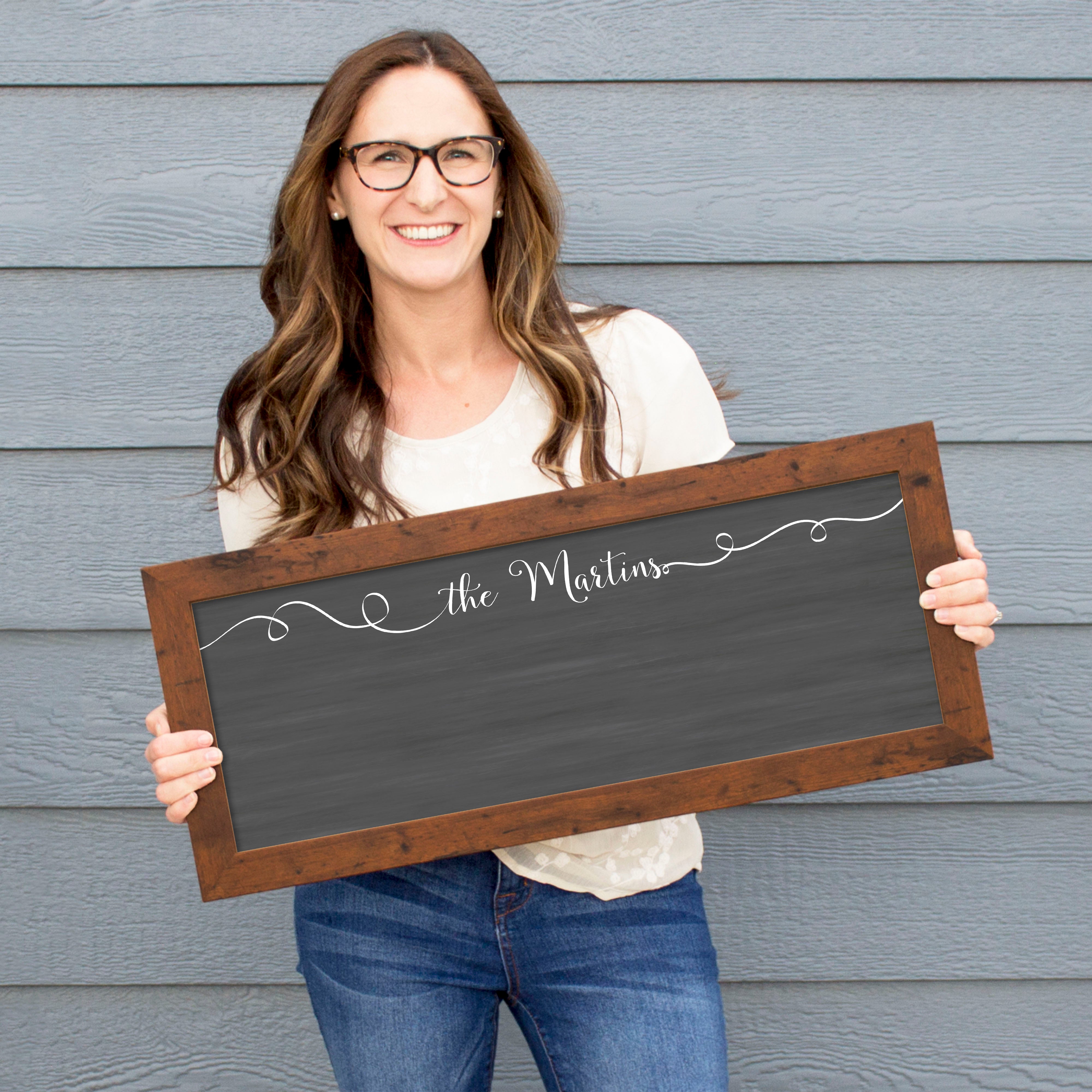 A framed dry-erase chalkboard calendar with a two month design format hanging on the wall