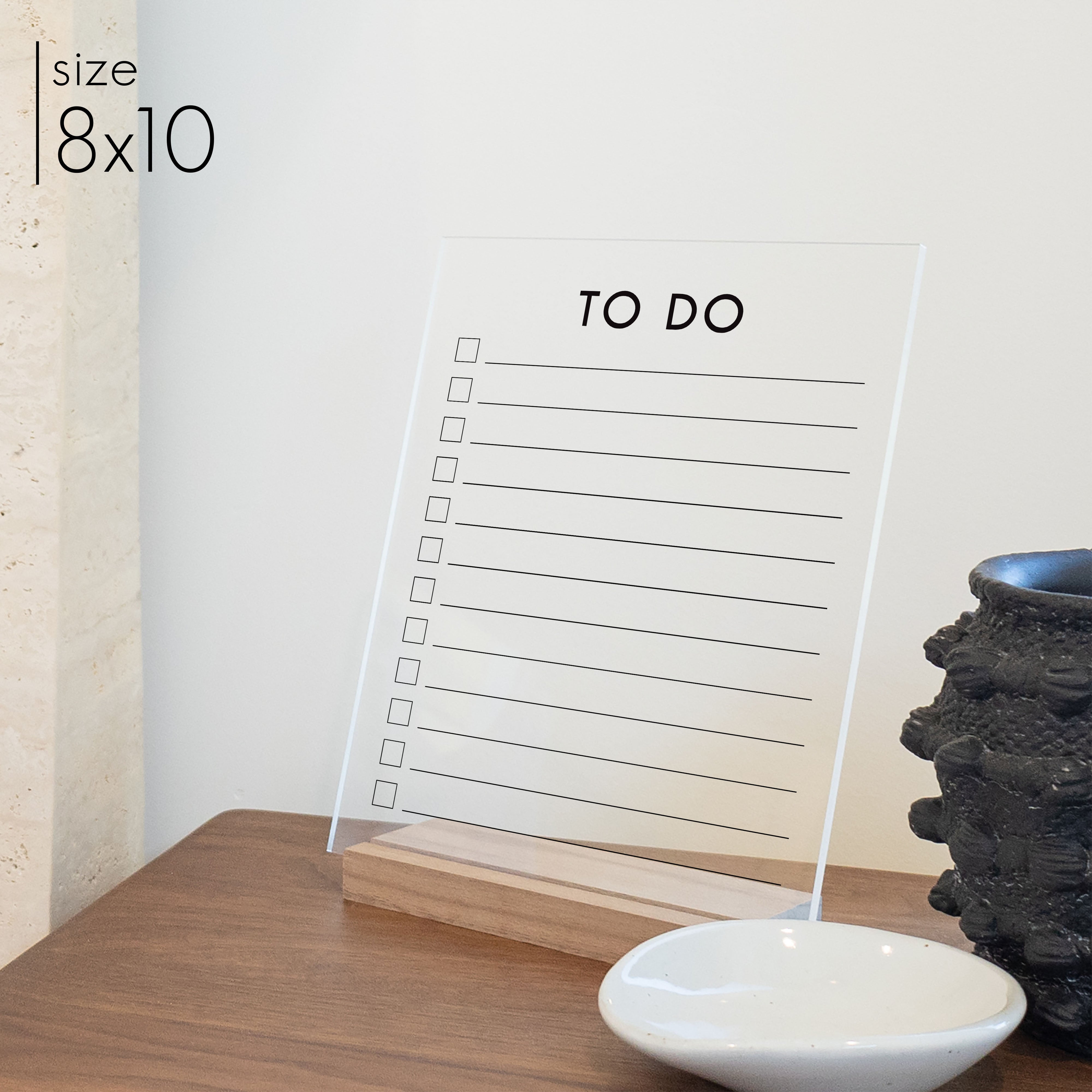 A large 8x10 to do list printed on clear acrylic with a wooden stand on a kitchen counter. 