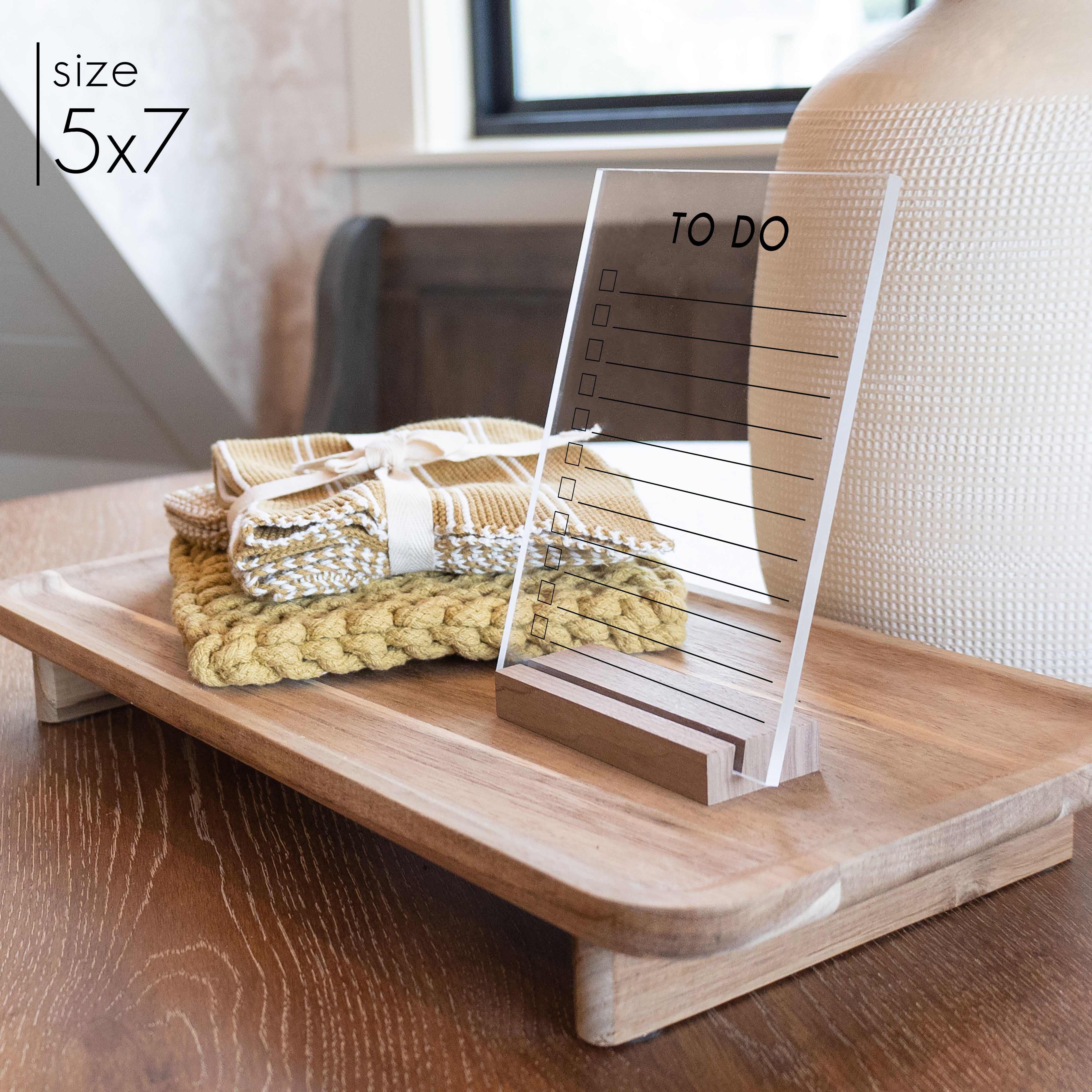 A 5x7 minimalist style to do list on clear acrylic with a wooden, walnut colored, stand.