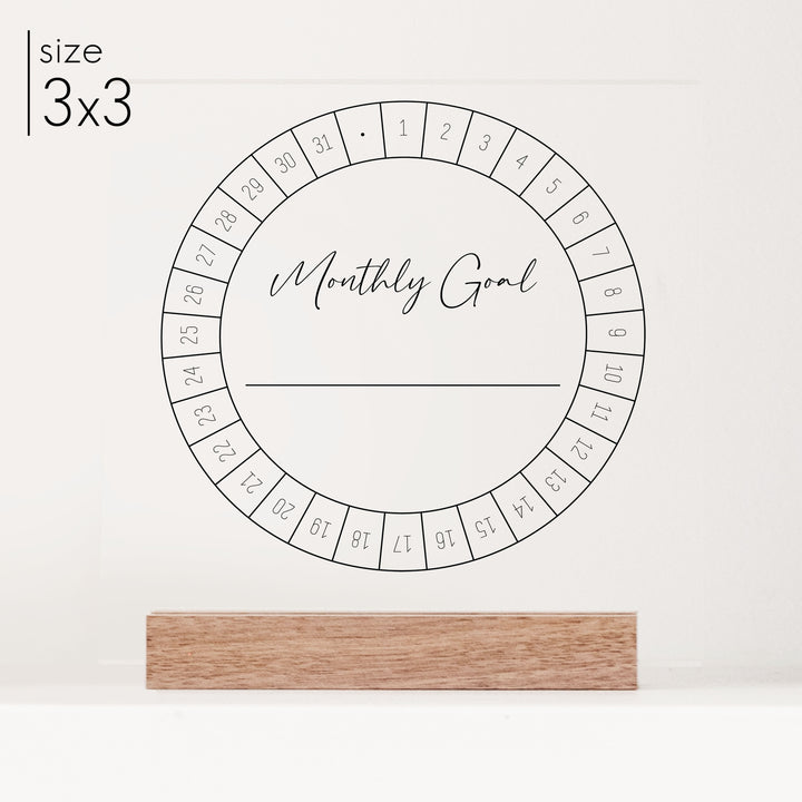 A close up of a 3x3 monthly goal tracker on a walnut colored wooden stand.